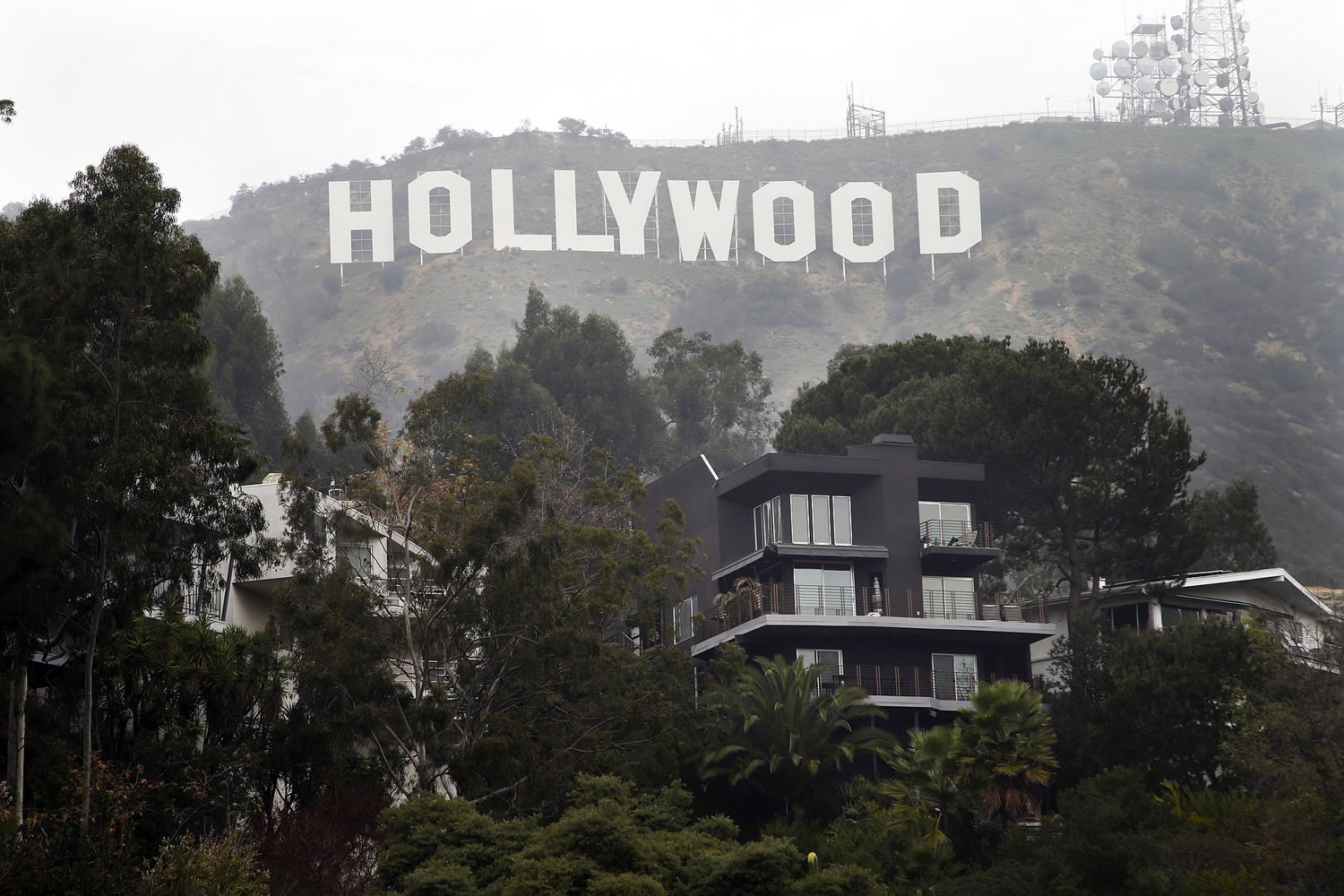 Homes sit on the hillside near the Hollywood Sign, Tuesday, Jan. 20, 2015, in Los Angeles. Hollywood Sign Seekers can't just take a bus or join a tour group to get there. Arriving at the landmark sign that towers magnificently over Los Angeles' skyline requires traipsing through a densely populated hillside neighborhood of 20,000 people and numerous multimillion-dollar homes located on steep, narrow, almost impassable streets. (AP Photo/Jae C.