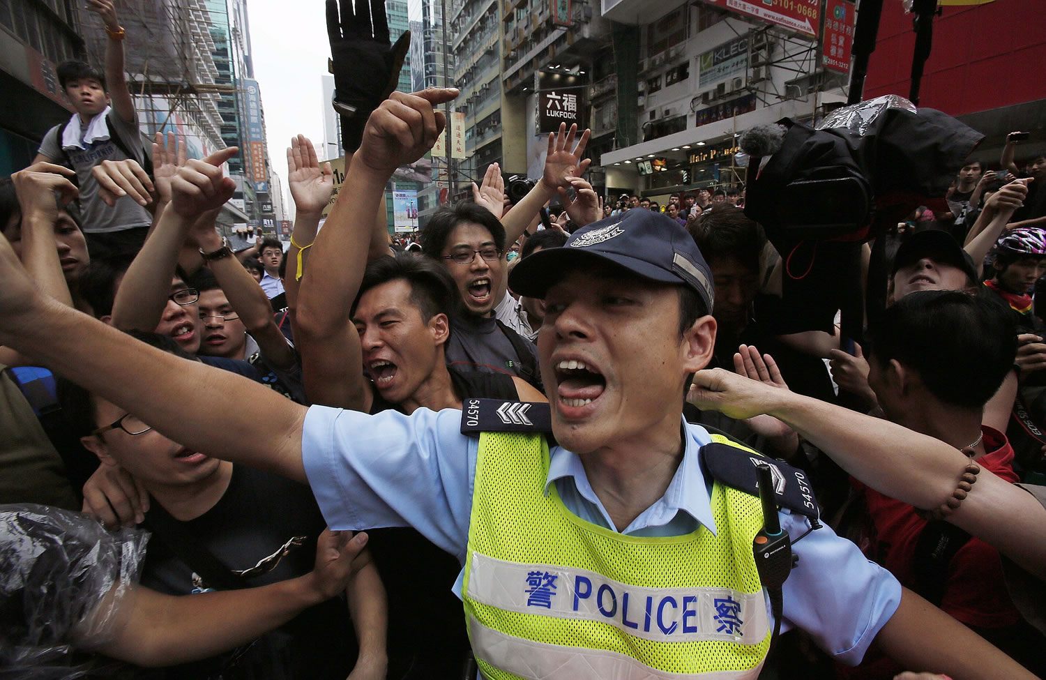 A police officer tries to hold back pro-democracy student protesters Saturday during a clash local residents in Mong Kok, Hong Kong.