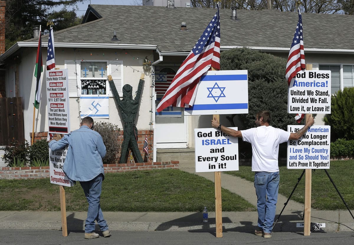 Robert Dixon, left, and Kraig Smith, demonstrate outside a home with swastikas displayed on the exterior Thursday in Sacramento, Calif.