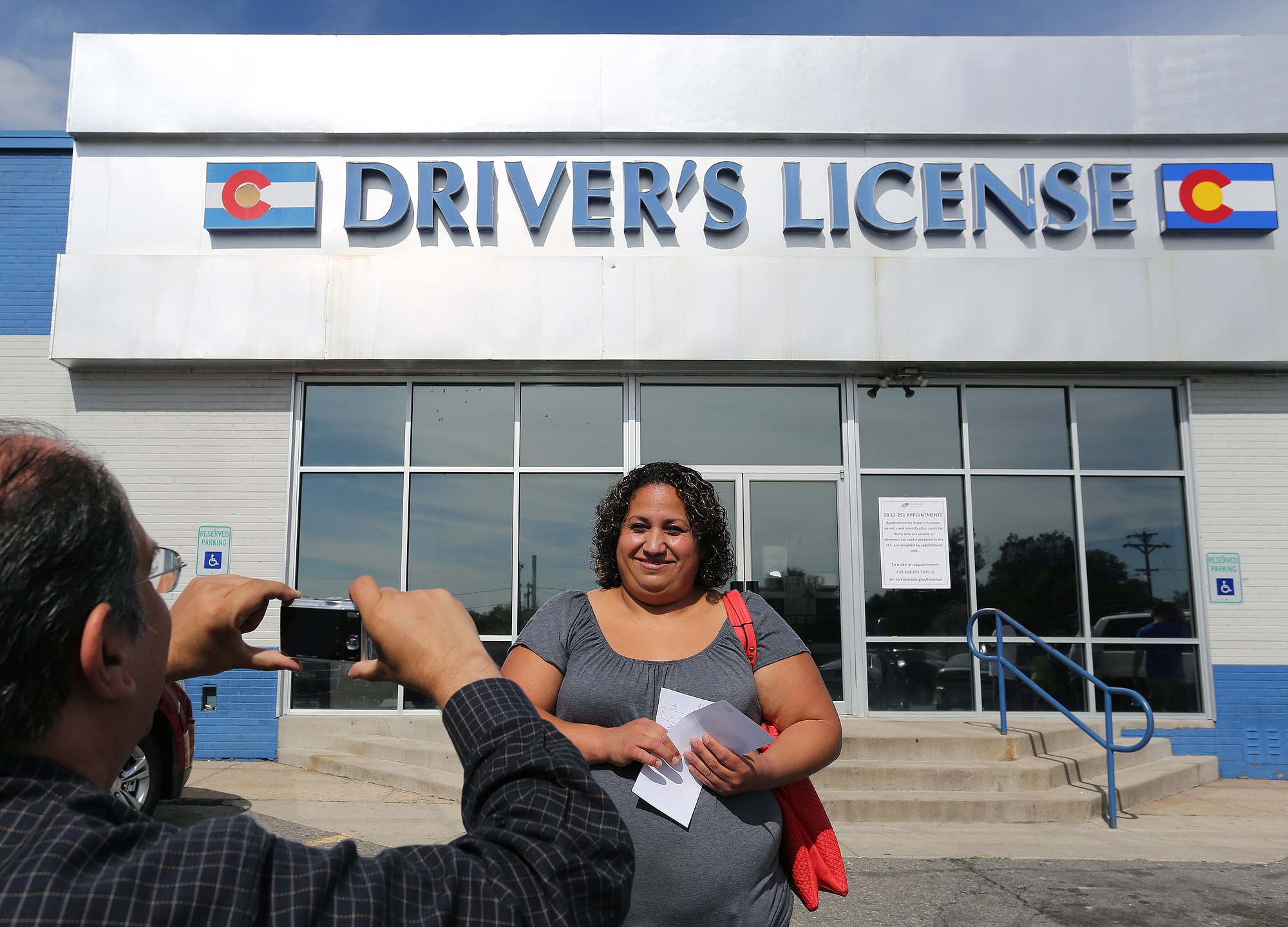 Immigrant and longtime resident in the United States Rosalva Mireles is photographed by Jesus Sanchez of Spanish language newspaper El Commercio, after Mireles was processed for her permanent driver's license, and received a temporary license, at a Department of Motor Vehicles office, in Denver, Friday Aug. 1, 2014. Colorado began issuing driver's licenses and identification cards on Aug. 1, 2014 to immigrants who are in the country, regardless of legal immigration status.
