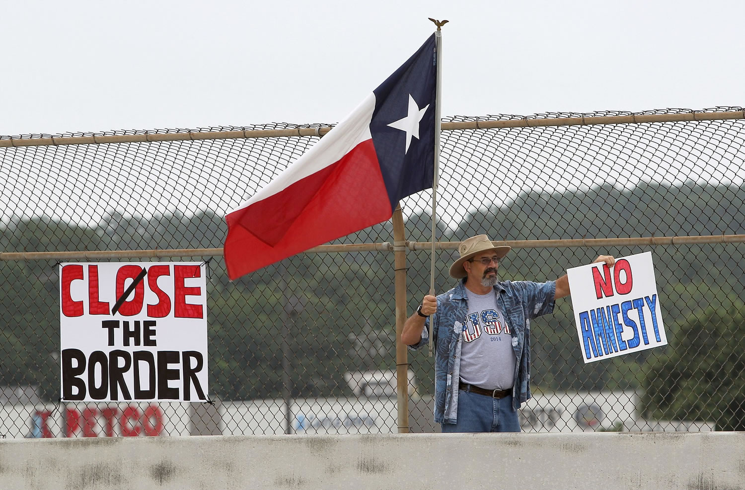 A protester waves a Texas flag and anti-immigration signs during a protest against people who immigrate illegally, Saturday in Conroe, Texas. Texas Gov.