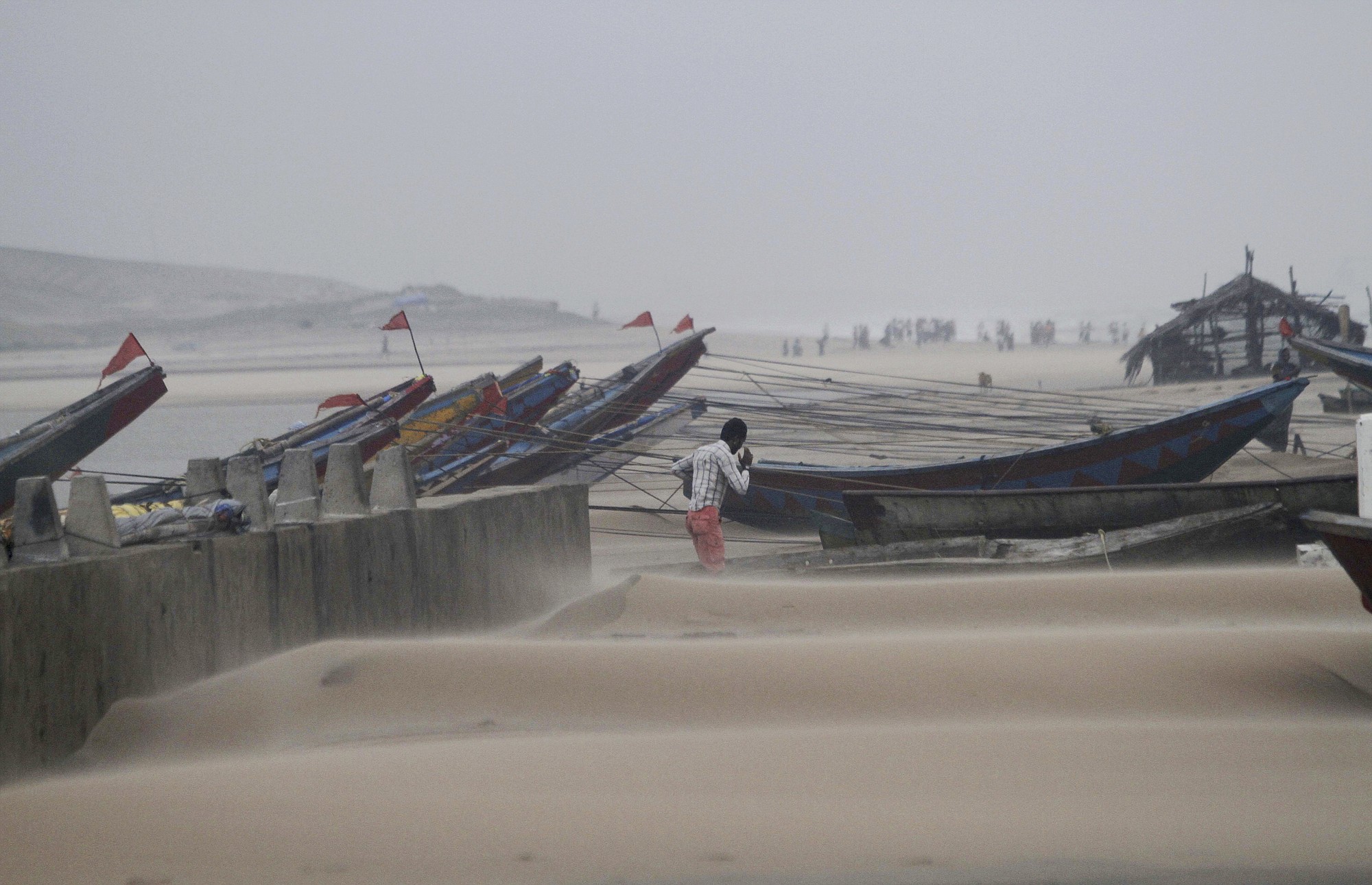 An Indian fisherman walks near the anchored fishing boats as strong winds blow a day after a powerful cyclone pounded the Bay of Bengal coast in Gopalpur, Orissa, about 285 kilometers north east of Visakhapatnam, India, on Monday.