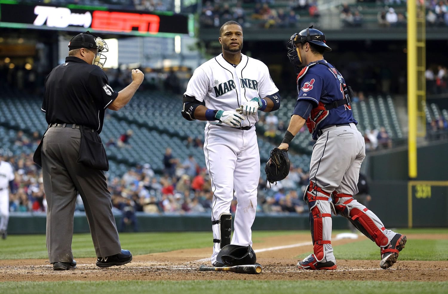 Home plate umpire Marvin Hudson, left, signals Seattle Mariners' Robinson Cano, center, out after he struck out swinging as Cleveland Indians catcher Yan Gomes stands next to them at the end of the fourth inning of a baseball game, Saturday, June 28, 2014, in Seattle. (AP Photo/Ted S.