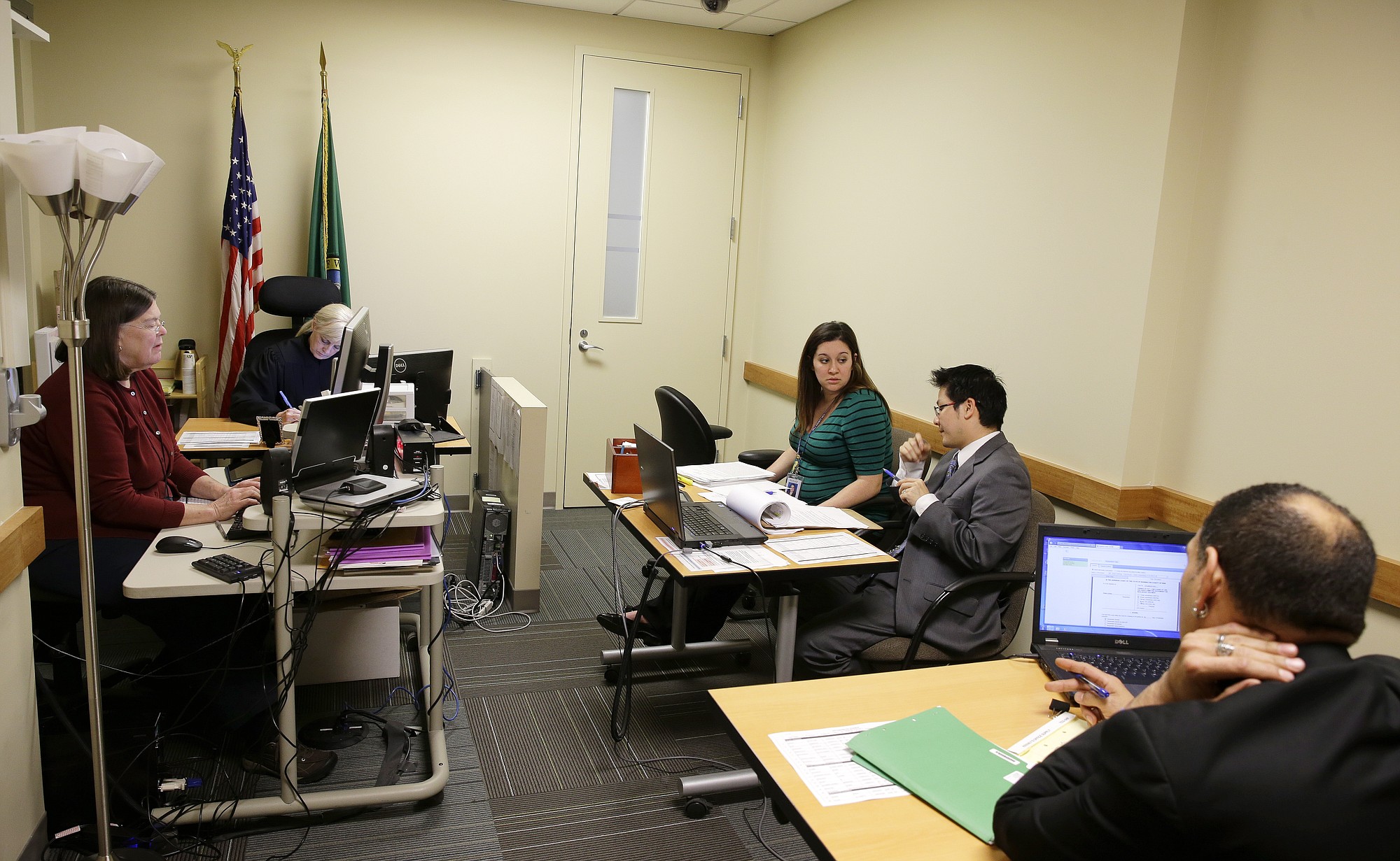 Court commissioner Hollis Holman, second from left, presides over a civil commitment court hearing held in a cramped former waiting room that has been turned into a second courtroom at Harborview Medical Center in Seattle.
