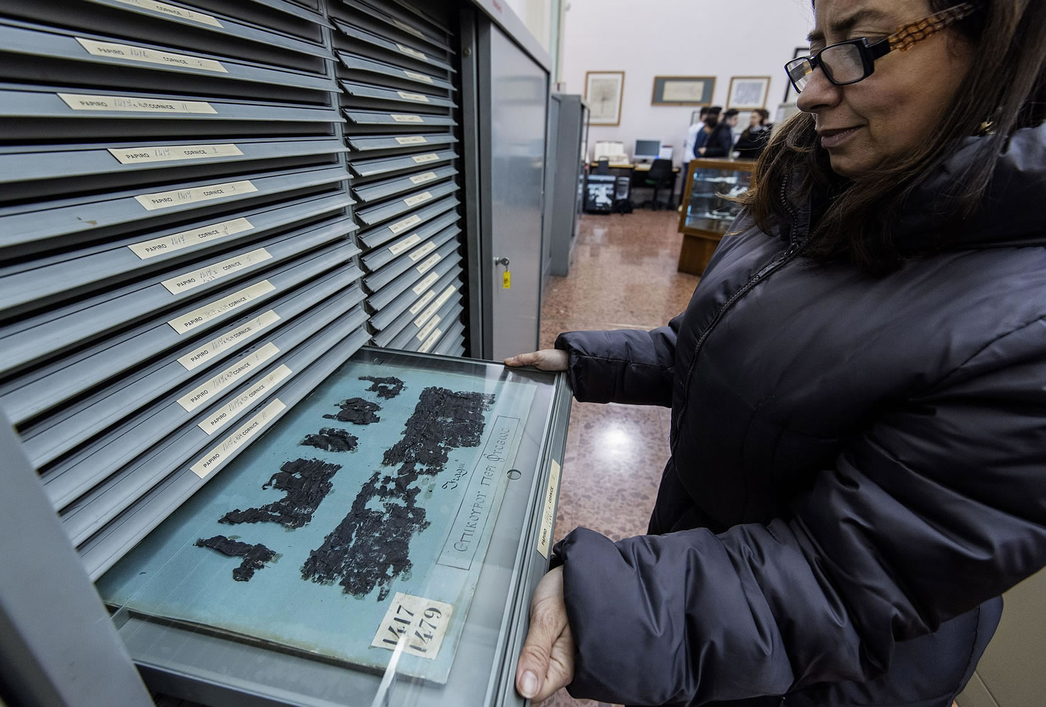 A woman shows the remains of an ancient papyrus at the Naples' National Library in Italy.