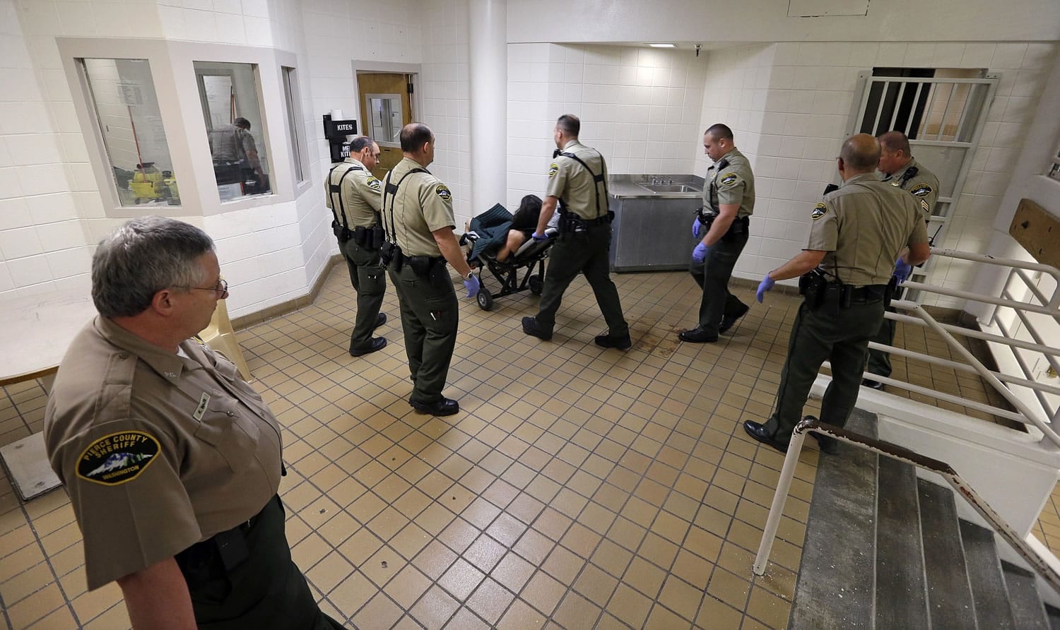 FILE -- In this file photo taken Oct. 15, 2014, corrections deputies transport an inmate, who had stripped himself naked and declined to walk, from the psychiatric unit of the Pierce County Jail to a hearing in Tacoma, Wash. Washington state judges have issued more than a dozen contempt orders against the state's health services agency and a psychiatric hospital for failing to treat mentally ill people held in jails for sometimes months. To date, the orders have topped $45,000.