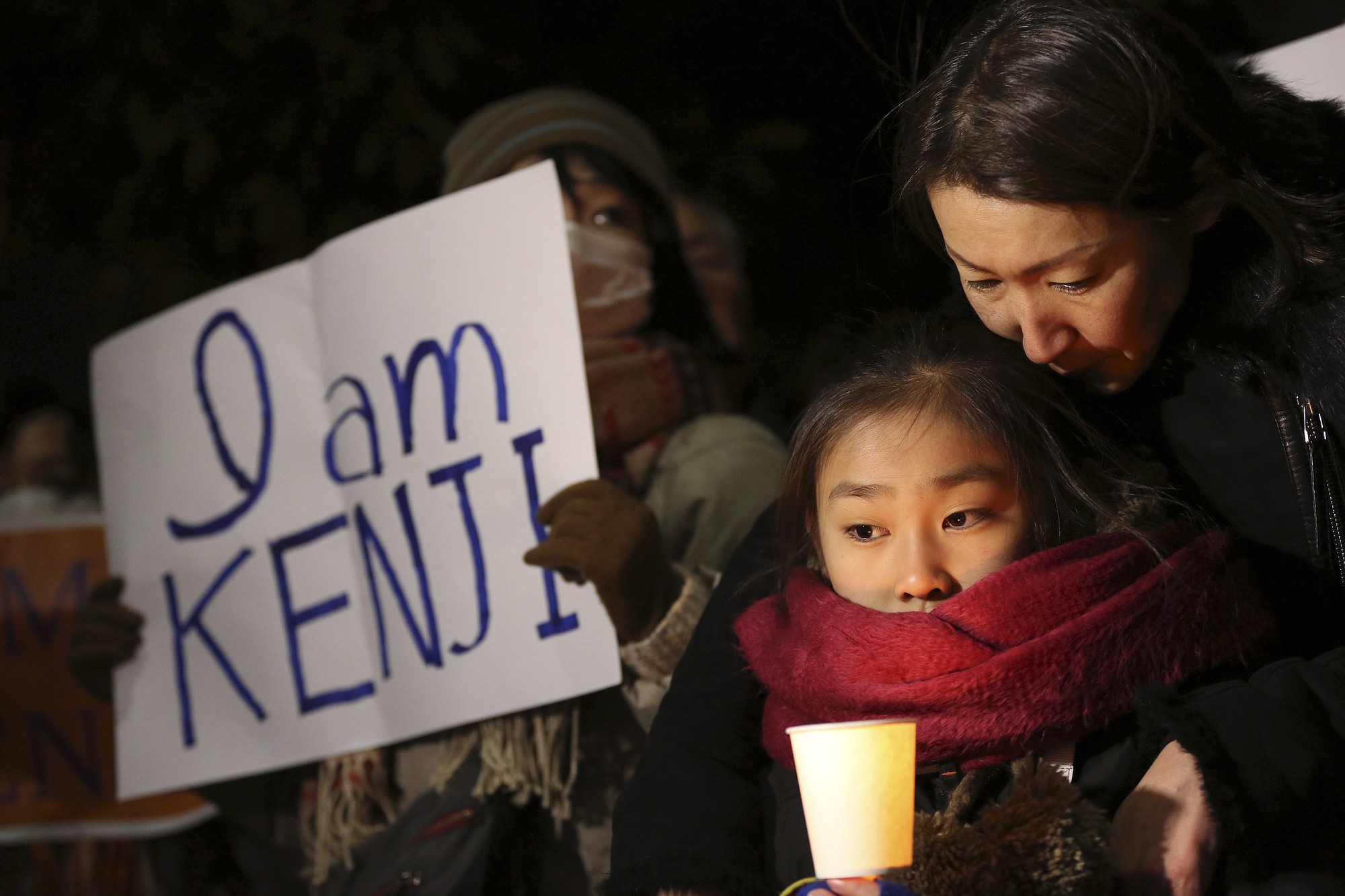A girl holding a candle joins others holding signs stating &quot;I am Kenji&quot; outside the prime minister's official residence in Tokyo on Wednesday as part of a demonstration in support of Kenji Goto who is held hostage by Islamic State group extremists.