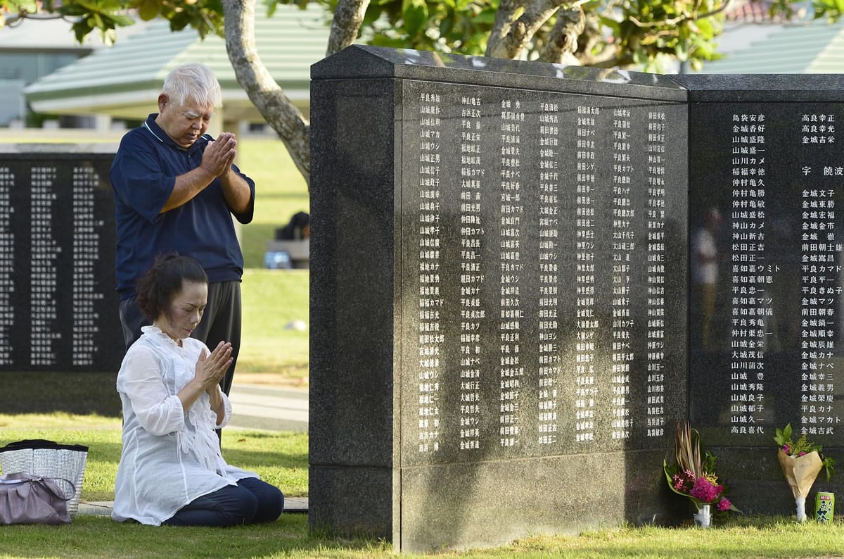 People pray Tuesday in Itoman in the Okinawa islands, Japan, in front of the Cornerstone of Peace.