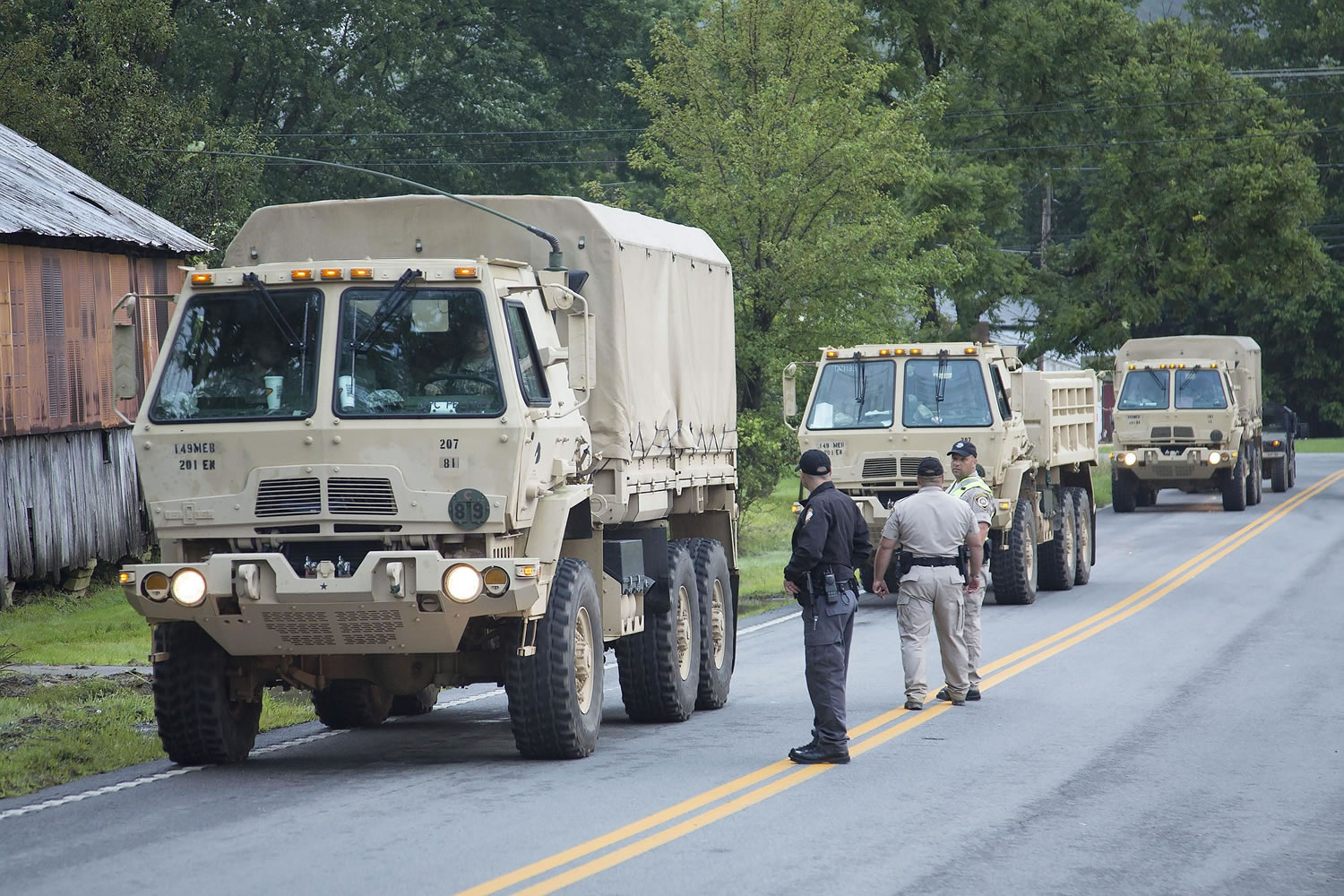 A National Guard caravan enters a checkpoint Wednesday on their way to help with search and recovery efforts after deadly flooding in Flat Gap, Ky.