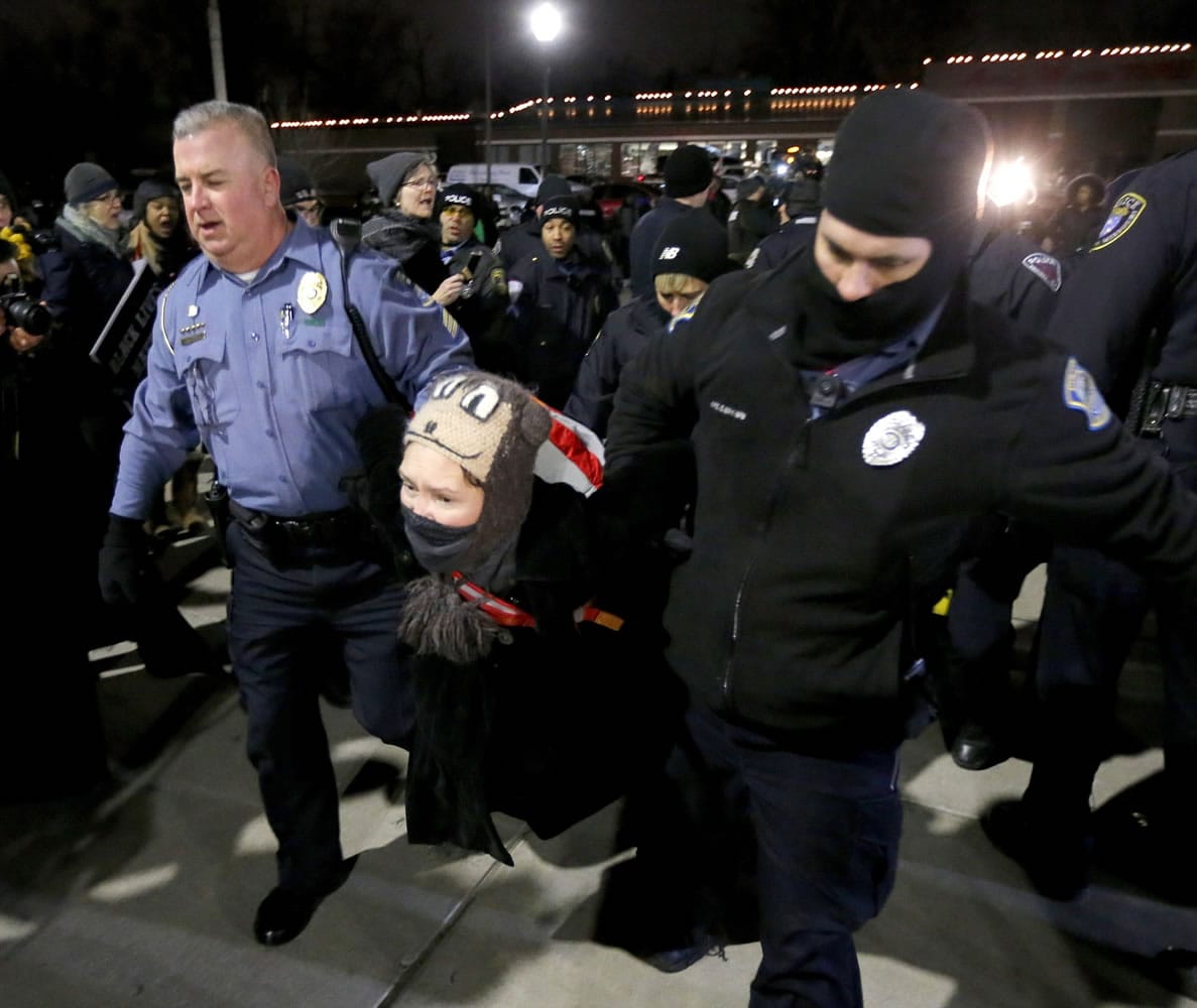 Ferguson, Mo., police officers take into custody a protester who was warned several times not to block the street outside the police station Wednesday in Ferguson.