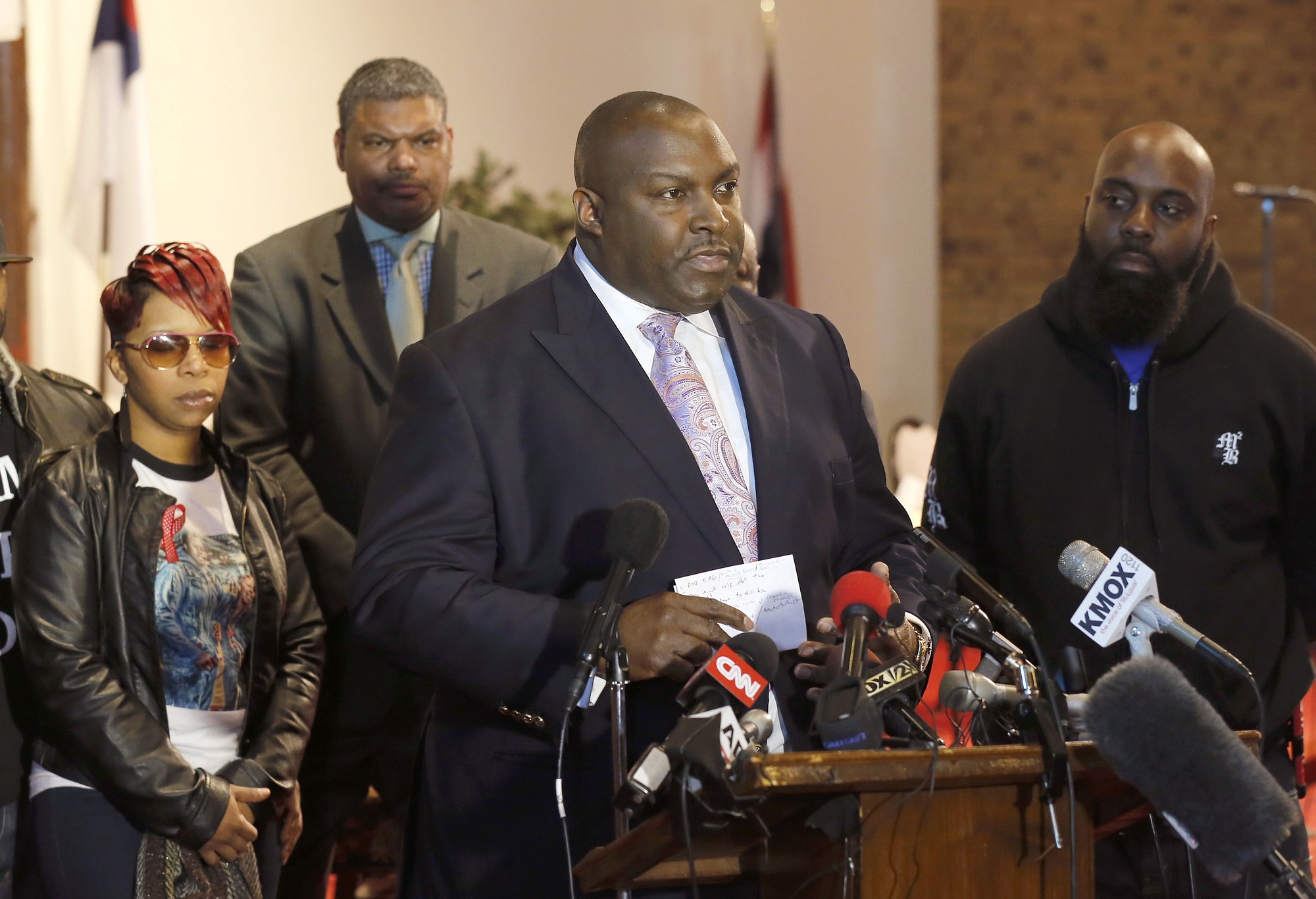 Attorney Daryl Parks, center, talks to reporters as Lesley McSpadden, left, and Michael Brown Sr., right, parents of 18-year-old Michael Brown Jr., listen during a news conference Thursday in Dellwood, Mo.