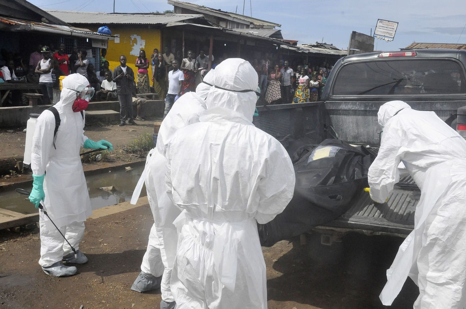 Health workers in protective gear load the body of a woman suspected of dying from the Ebola virus, into a pickup truck near the area of Freeport in Monrovia, Liberia, on Wednesday.