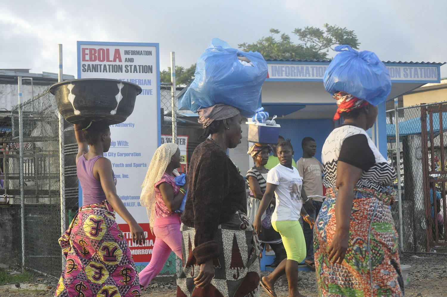 Liberia women walk past a sign warning people of the deadly Ebola virus in Monrovia, Liberia