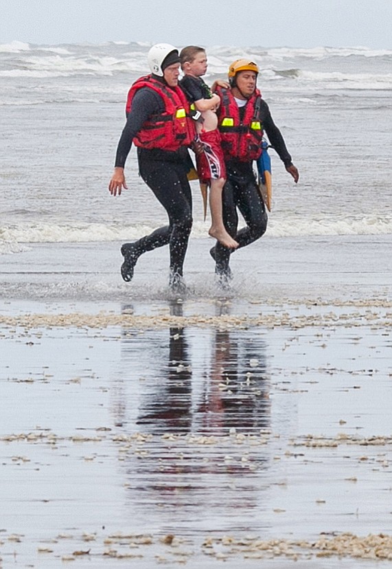 Surf rescue swimmers Julez Orr and Eddie Mendez carry an 11-year-old boy to the shore at Long Beach after rescuing him from the ocean Thursday.