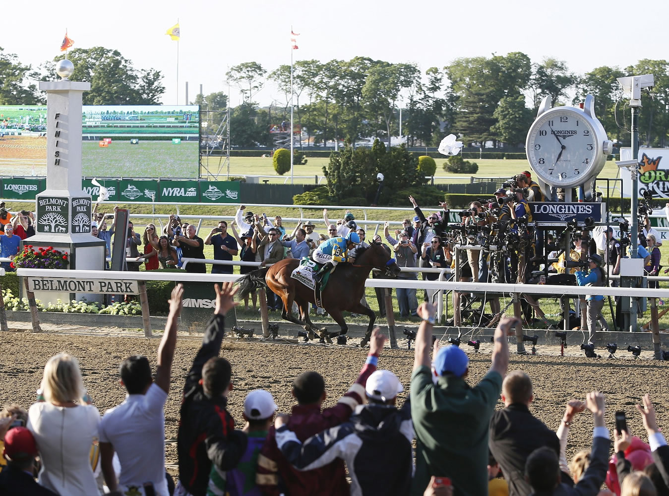 STUART RAMSON/Invision for Longines/AP Images
People cheer as Victor Espinoza rides American Pharoah to victory at the 147th Belmont Stakes on Saturday at Belmont Park in Elmont, N.Y.