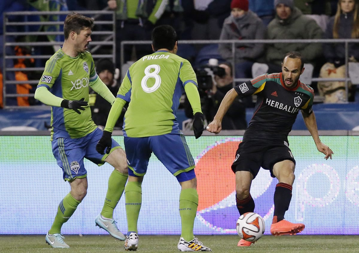 Los Angeles Galaxy's Landon Donovan, right, kicks away from Seattle Sounders' Gonzalo Pineda (8) and Brad Evans, left, in the first half of the second leg of the MLS Western Conference final, Sunday, Nov. 30, 2014, in Seattle. (AP Photo/Ted S.