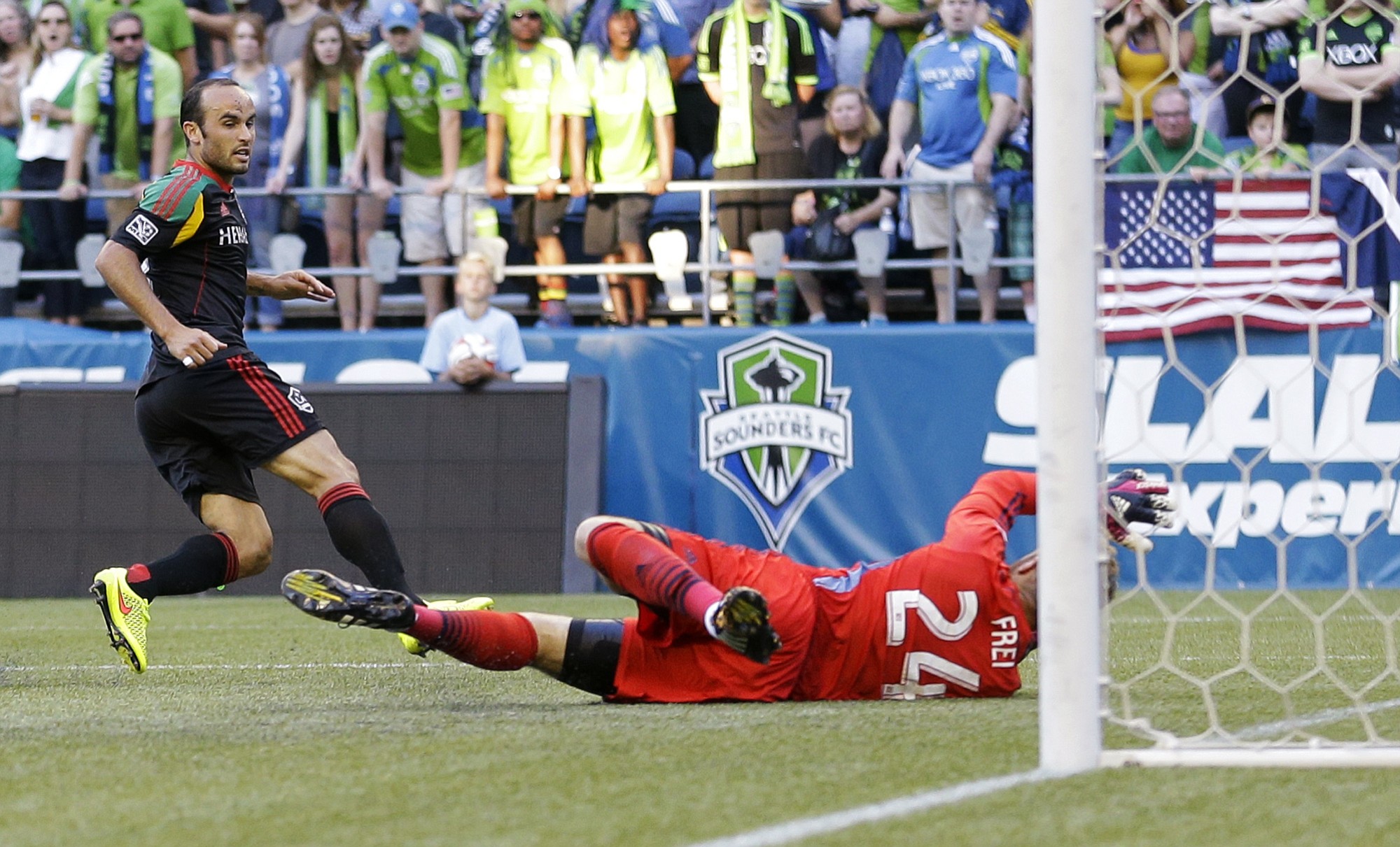 Los Angeles Galaxy's Landon Donovan, left, scores a goal on Seattle Sounders goalkeeper Stefan Frei, right, in the first half Monday, July 28, 2014, in Seattle. (AP Photo/Ted S.