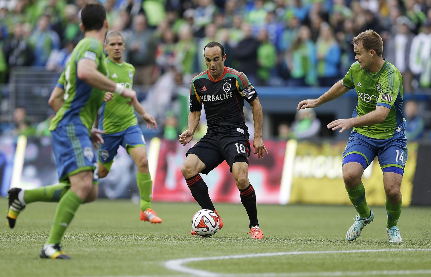 Los Angeles Galaxy midfielder Landon Donovan, center, dribbles the ball as Seattle Sounders' Chad Marshall, right, closes in during the first half Saturday, Oct. 25, 2014, in Seattle. (AP Photo/Ted S.