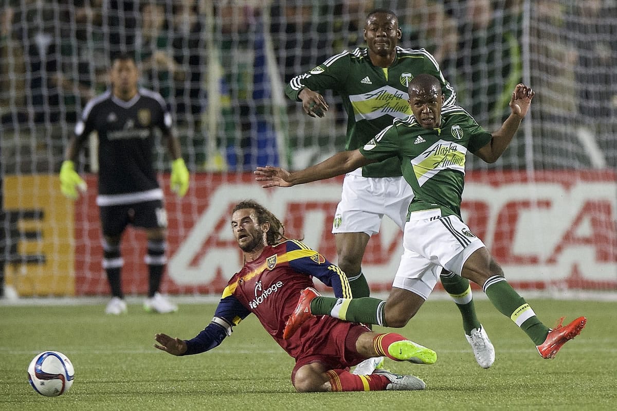 Kyle Beckerman, lower left, of Real Salt Lake, slide tackles Darlington Nagbe, right, of the Portland Timbers, during the first half Saturday, March 7, 2015, in Portland.