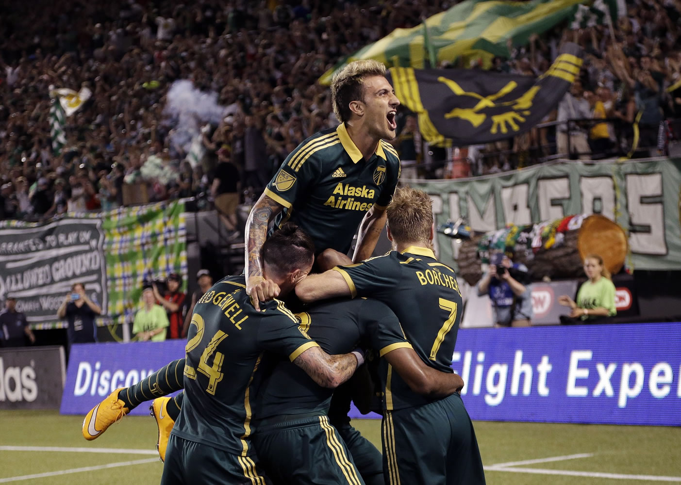 Portland Timbers forward Maximiliano Urruti leaps on top of teammates and yells to the fans as they celebrate a goal during the second half of an MLS soccer game against the New England Revolution  in Portland, Ore., Saturday, June 6, 2015.   Portland won 2-0.