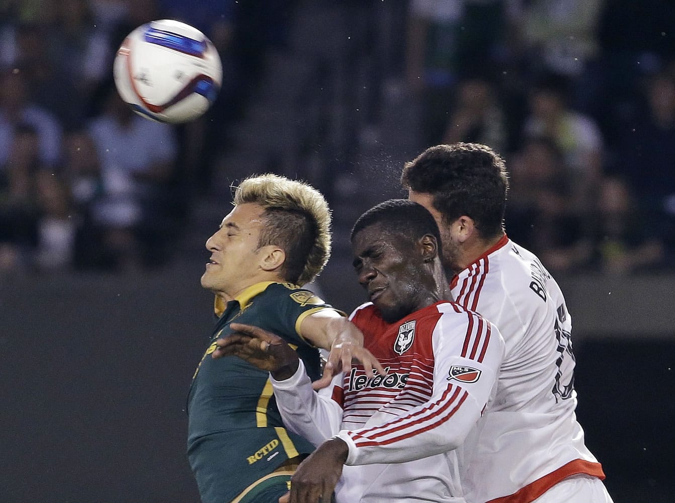 Portland Timbers forward Maximiliano Urruti, left, heads the ball away from D.C. United's Steven Birnbaum, right, and Kofi Opare during the second half of an MLS soccer game in Portland, Ore., Wednesday, May 27, 2015.  Urruti scored Portland's lone goal as Portland won 1-0.