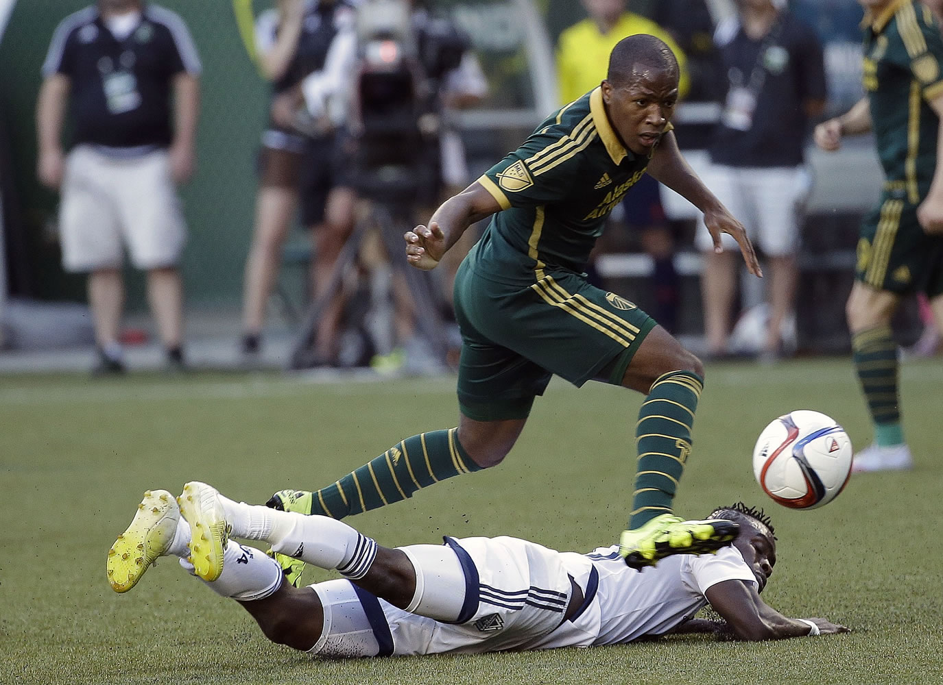 Portland Timbers forward Darlington Nagbe, top, leaps over Vancouver Whitecaps midfielder Gershon Koffie as he chases the ball during the first half of an MLS soccer game in Portland, Ore., Saturday, July 18, 2015.