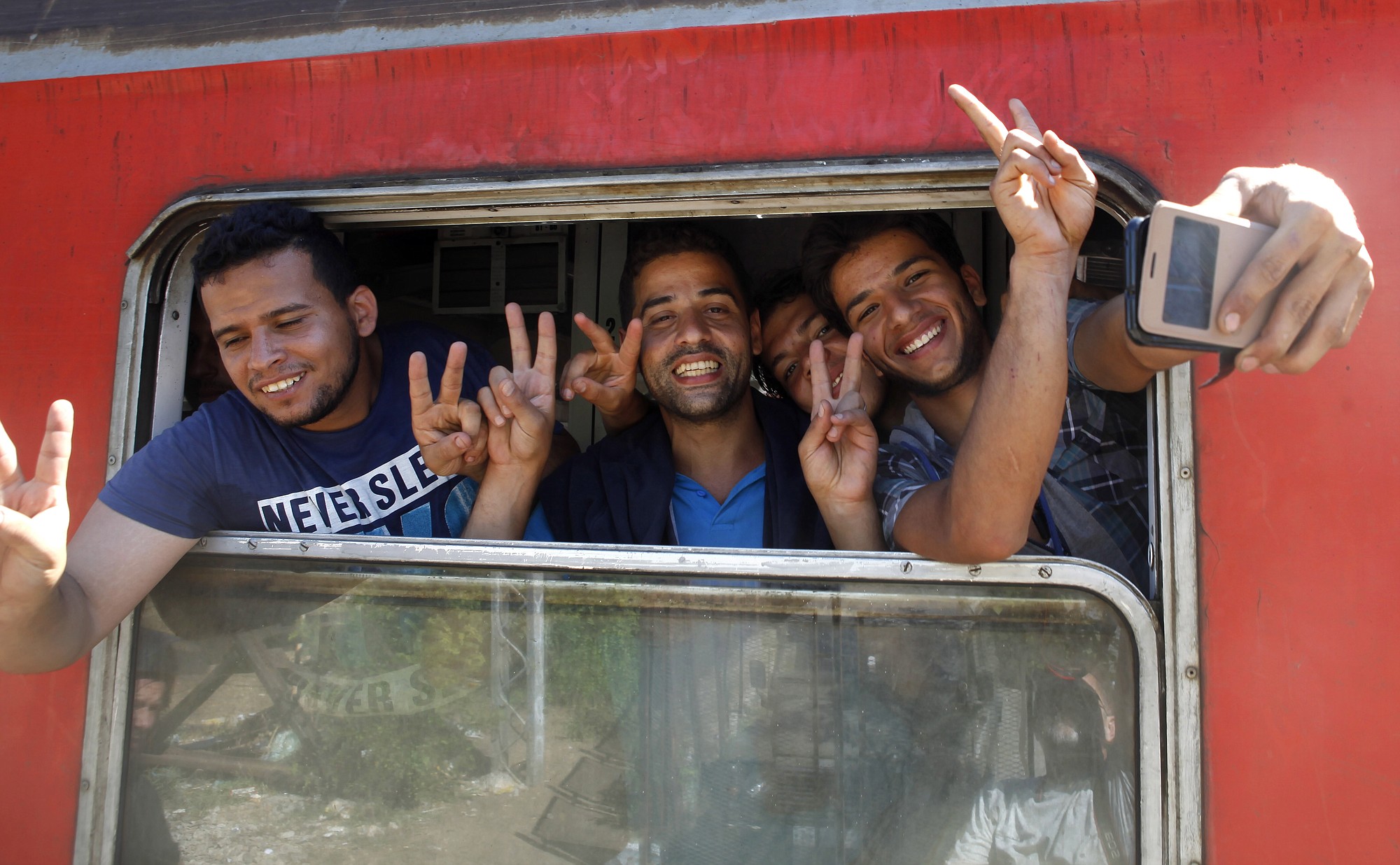Migrants from Syria take a selfie and flash victory signs from a window of a train that would take them towards Serbia, at the railway station in the southern Macedonian town of Gevgelija, on Monday.