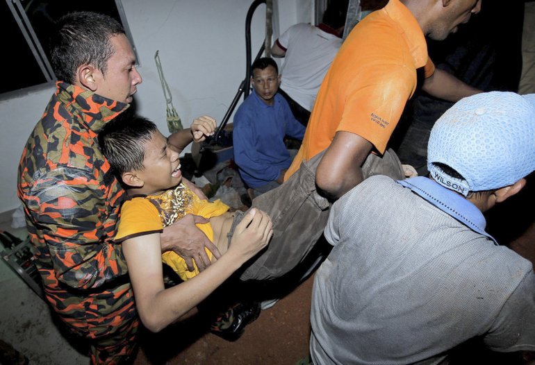 Rescuers today carry a survivor from a landslide that half-buried an orphanage house in Hulu Langat in central Selangor state, outside Kuala Lumpur, Malaysia.
