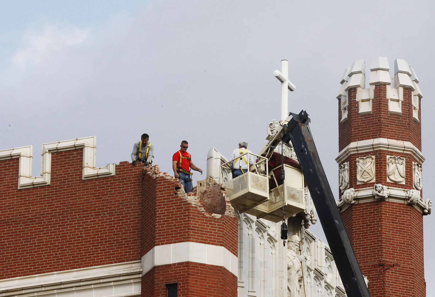 Maintenance workers inspect the damage to one of the spires on Benedictine Hall at St. Gregory's University in Shawnee, Okla., on Nov.