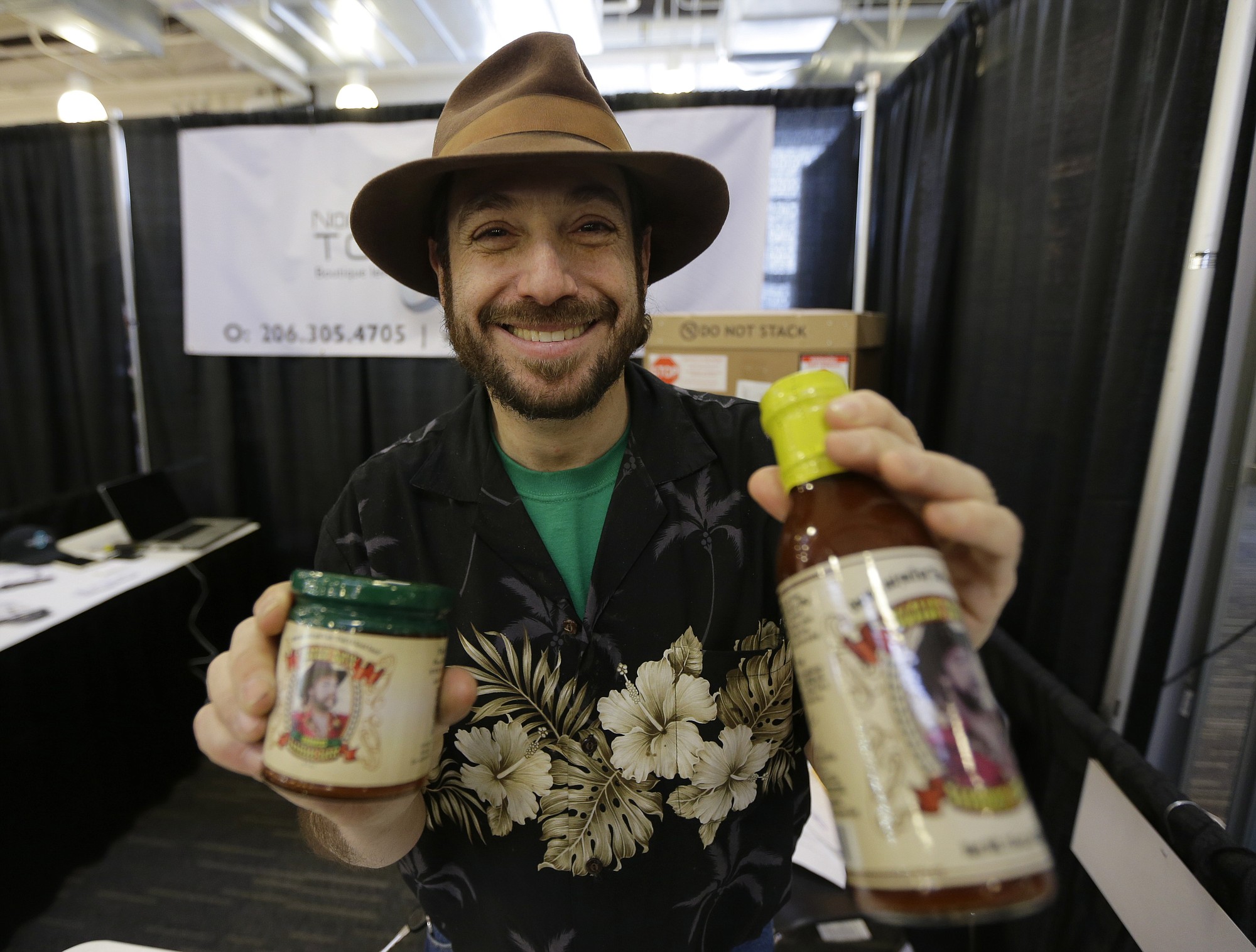 Eric Schneider, maker of &quot;The Sauce Guy&quot; barbecue sauce, holds the standard version of his sauce, at right, and a new version that is infused with marijuana hash oil.