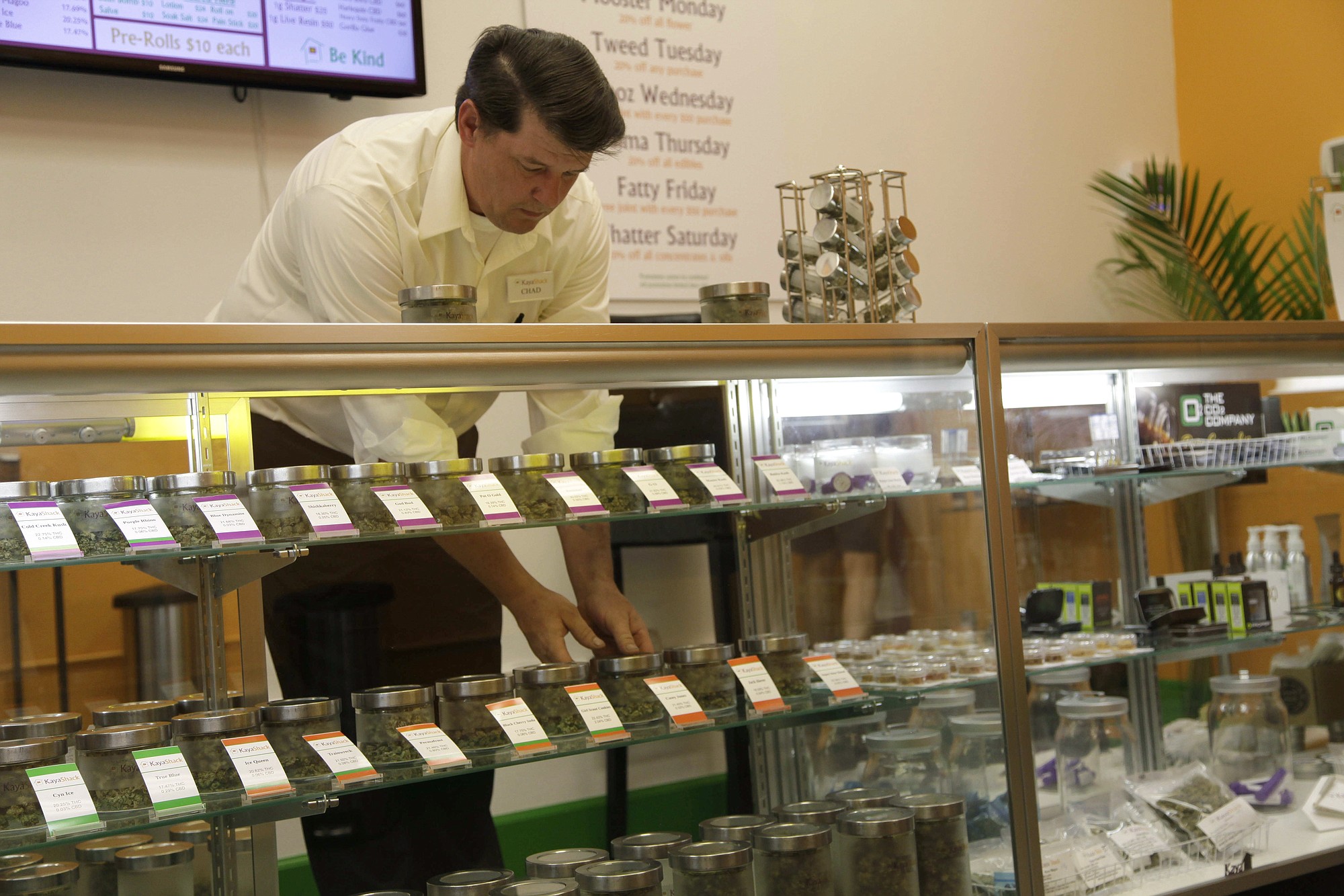 FILE - In this June 26, 2015 file photo, Chad Craig , an employee at the medical marijuana dispensary Kaya Shack, puts away jars of marijuana flowers on the dispensary's shelves in Portland, Ore. Oregon applications for permits to open new medical marijuana dispensaries are growing as the Oct. 1 date approaches allowing them to offer retail sales of marijuana to anyone over 21.