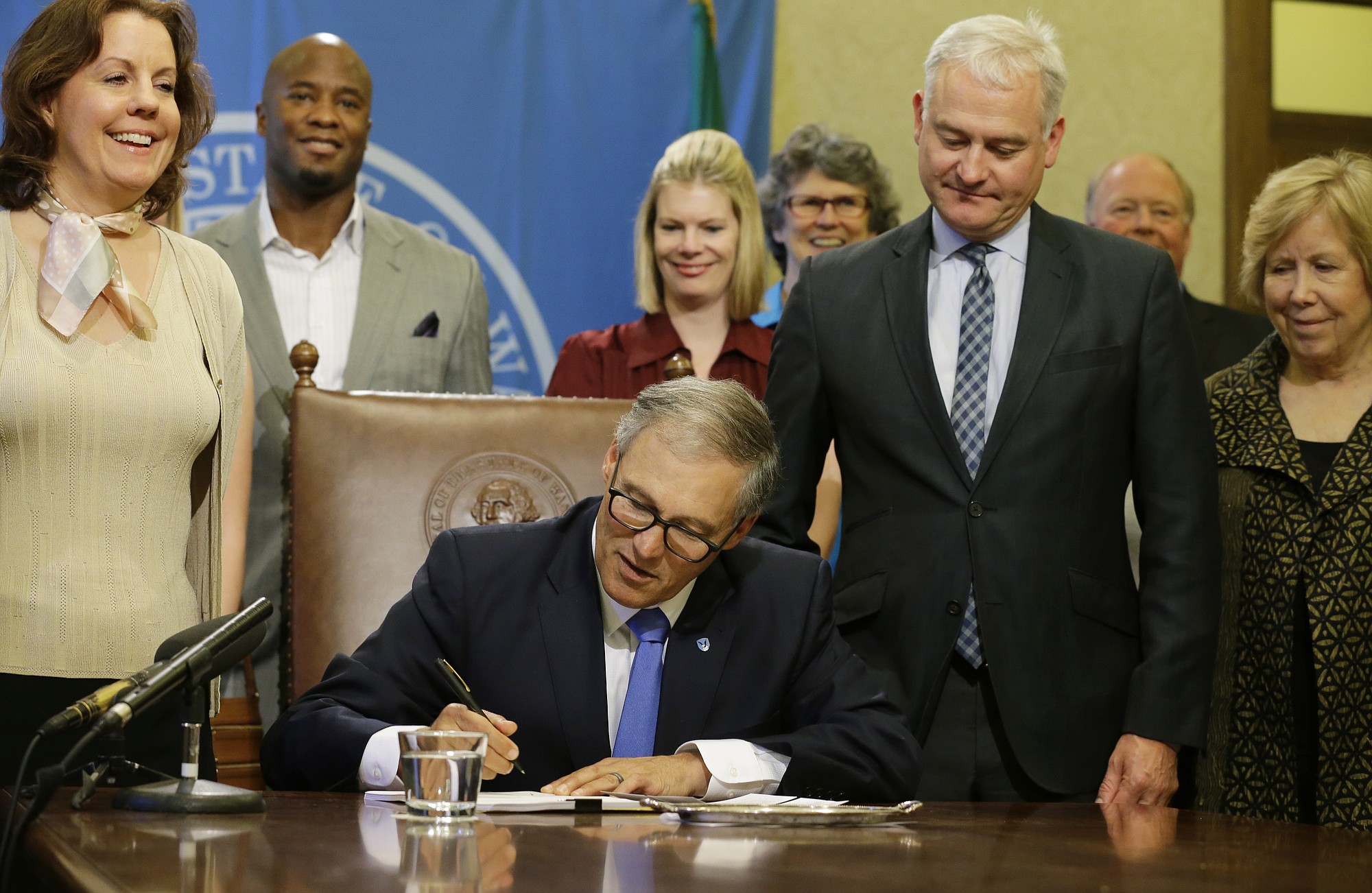 Washington Gov. Jay Inslee, center, signs a bill Tuesday at the Capitol in Olympia. The measure makes changes to Washington state's new recreational marijuana law, including revising the market's tax structure. Looking on are Sen. Ann Rivers, R-La Center, left, and Sen.