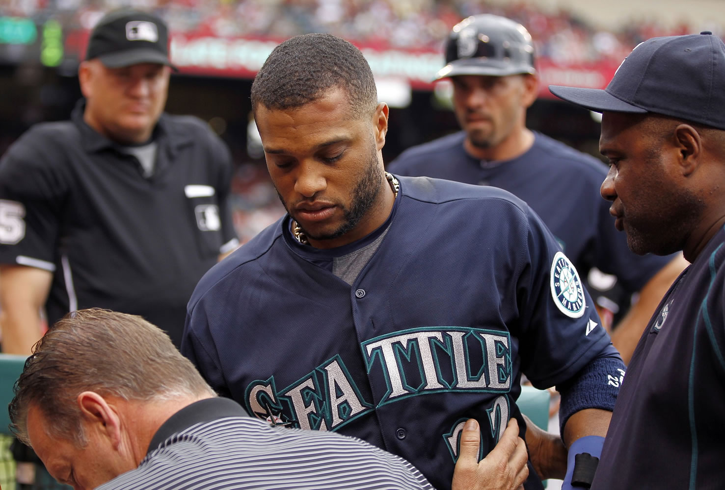 Seattle's Robinson Cano, center, is taken from the bench with a knot on his forehead after an overthrow by the Los Angeles Angels during infield warmups to begin the seventh inning in Anaheim, Calif., Saturday, June 27, 2015. Cano was removed from the game.