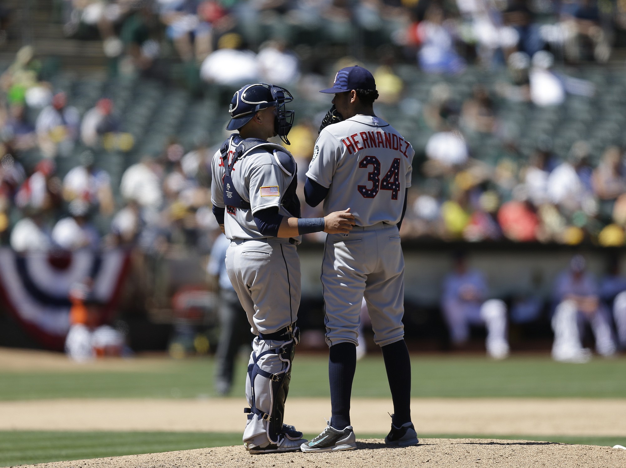 Seattle Mariners' Felix Hernandez (34) and Jesus Sucre speak on the mound in the third inning against the Oakland Athletics on Saturday, July 4, 2015, in Oakland, Calif.