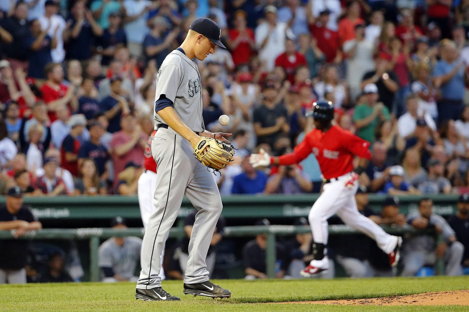 Seattle Mariners starting pitcher Mike Montgomery tosses a new ball in the air as Boston Red Sox's Rusney Castillo, right, rounds the bases after his two-run home run during the first inning at Fenway Park in Boston Friday, Aug. 14, 2015.