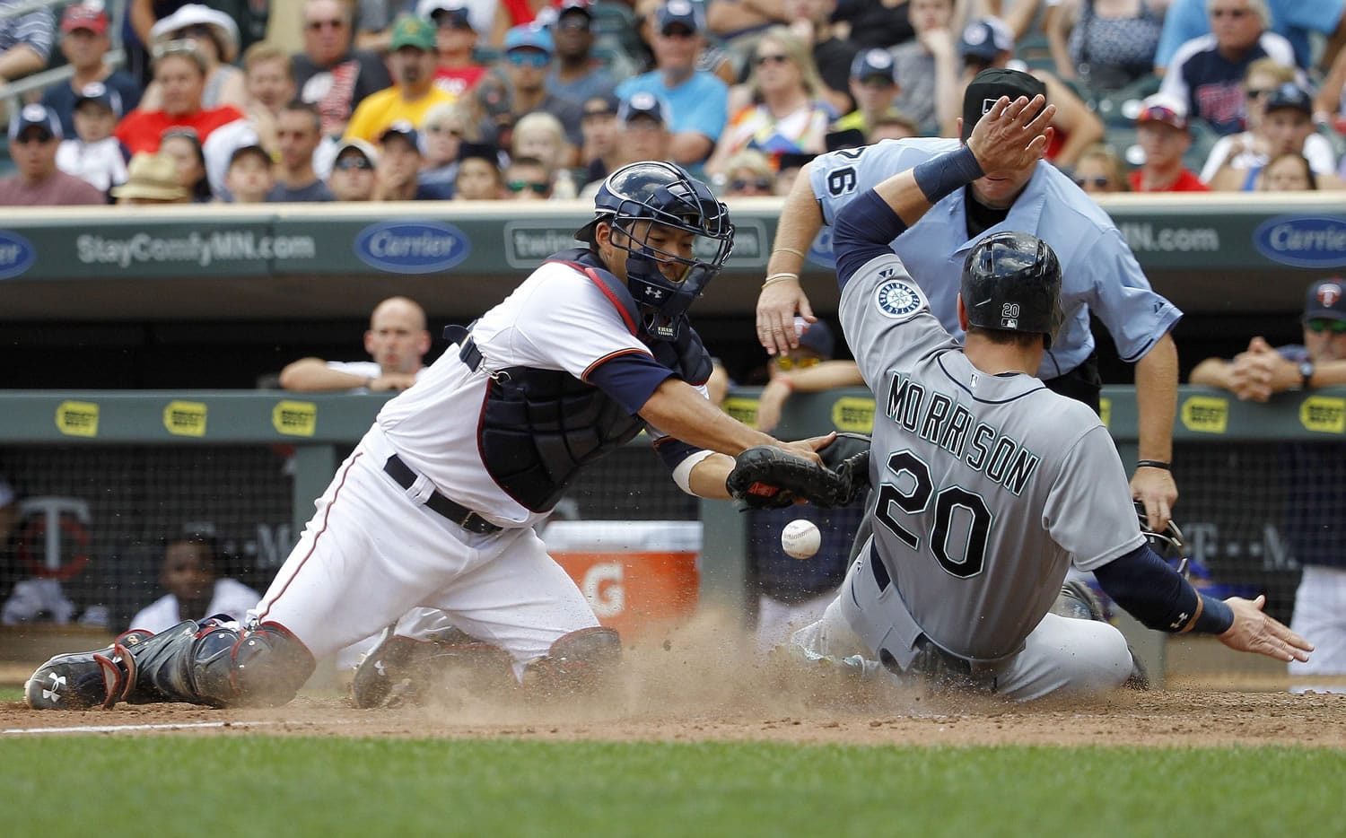 Seattle Mariners' Logan Morrison, right, scores on a single by Mariners' Austin Jackson as Minnesota Twins catcher Kurt Suzuki, left, bobbles the throw from left field during the 11th inning Sunday at Minneapolis. The Mariners won 4-1.