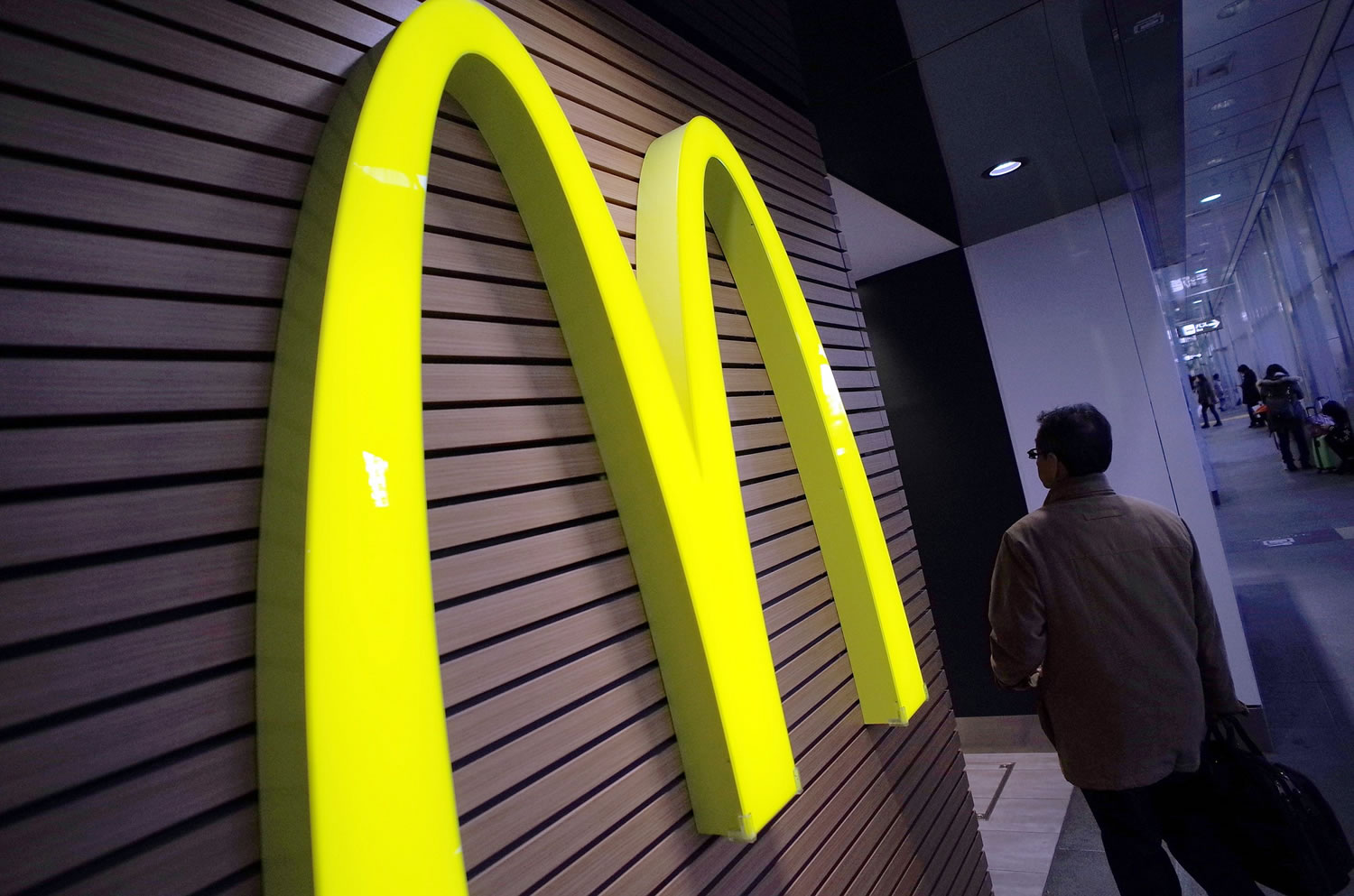 A man walks by a McDonald's logo in front of its restaurant in Tokyo.