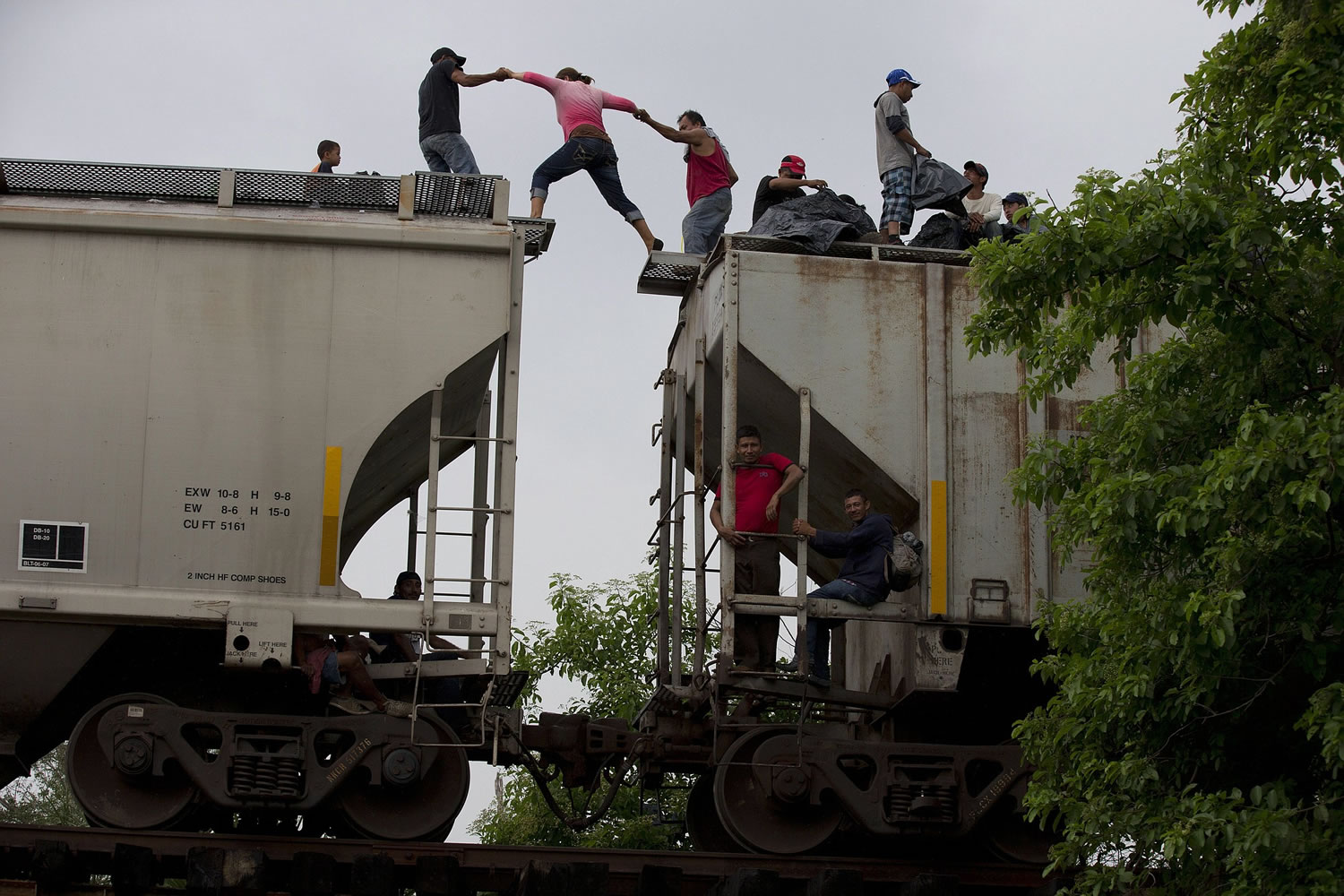 A woman is helped from one boxcar to another, as Central American migrants wait atop the train they were riding north, hours after it suffered a minor  derailment in a remote wooded area outside Reforma de Pineda, Chiapas state, Mexico.