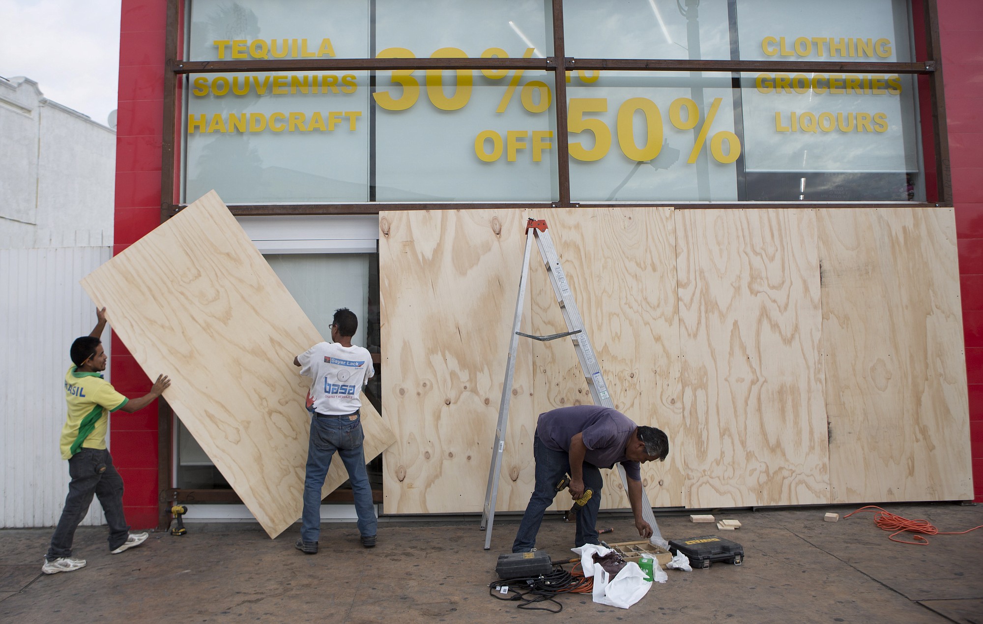 Workers board over storefront windows Sunday in preparation for tropical storm Blanca in Cabo San Lucas, Mexico.