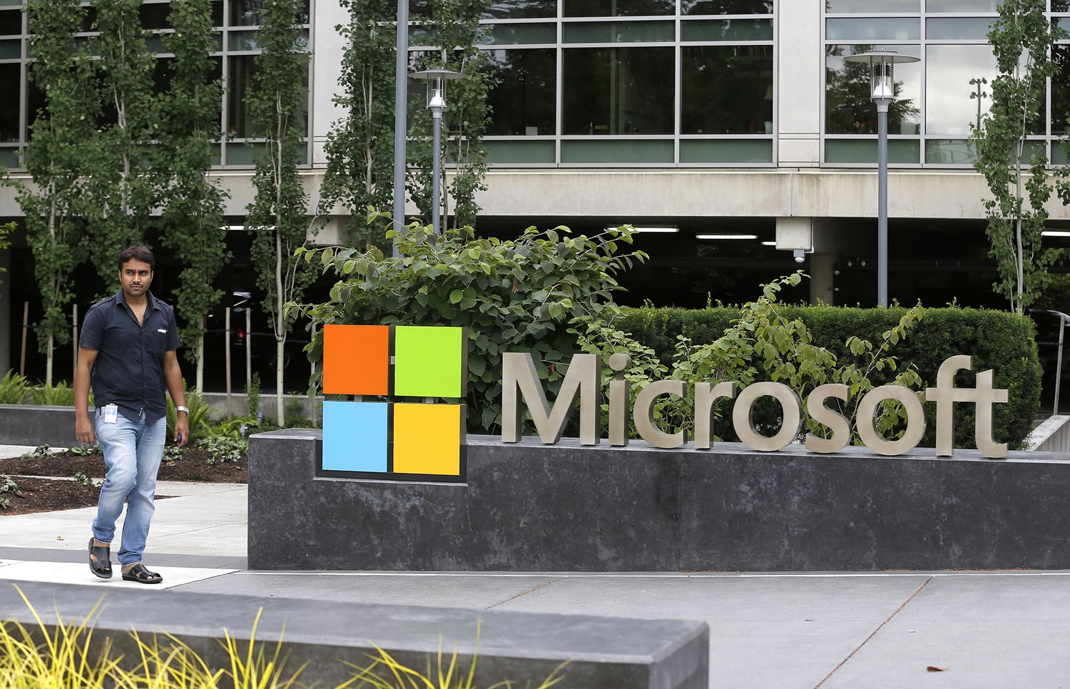 A worker walks past a Microsoft Corp. sign outside the Microsoft Visitor Center in Redmond.