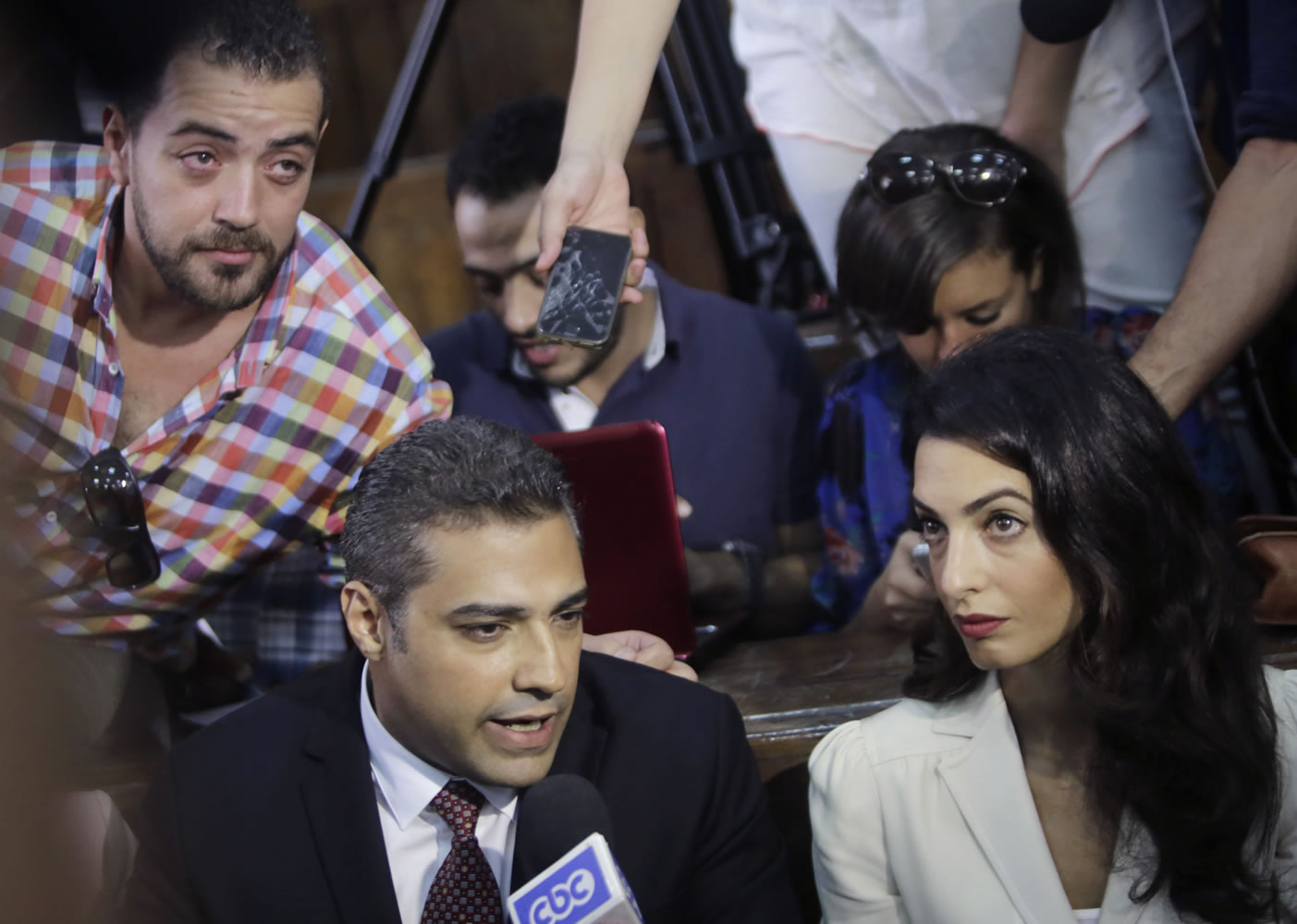 Canadian Al-Jazeera English journalist Mohammed Fahmy, left, his lawyer Amal Clooney and his Egyptian colleague Baher Mohammed, at top left, speak to media before their verdict in a courtroom in Tora prison in Cairo, Egypt, Saturday, Aug. 29, 2015. An Egyptian court on Saturday sentenced three Al-Jazeera English journalists to three years in prison, the last twist in a long-running trial criticized worldwide by press freedom advocates and human rights activists.
