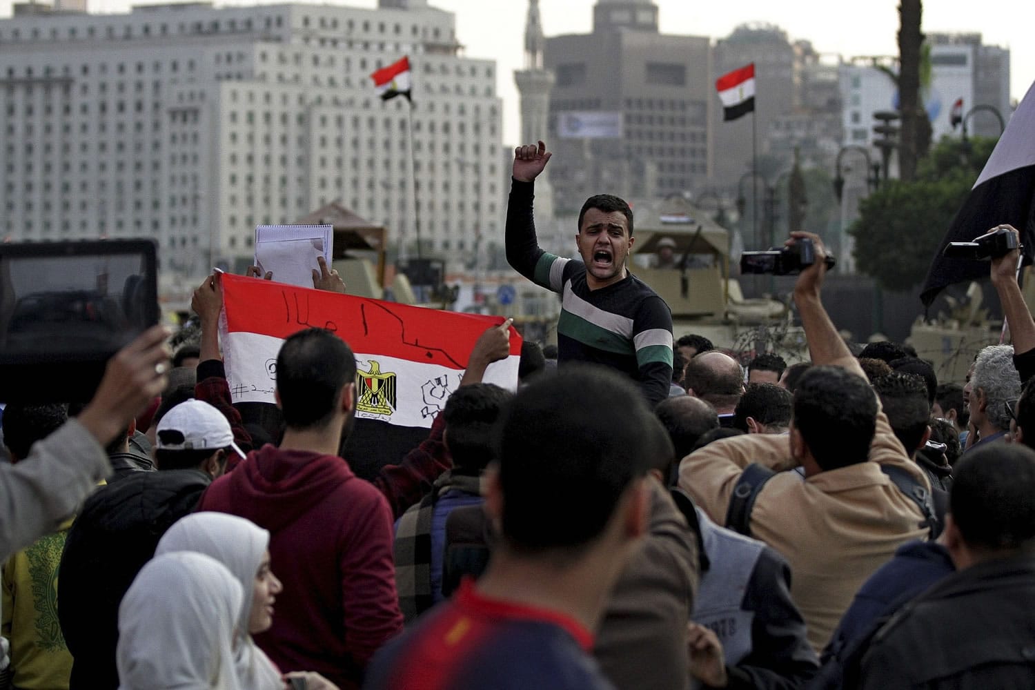 Protesters shout anti-government slogans and hold a national flag with &quot;God is great written on it,&quot; after a judge on Saturday dismissed the case against former President Hosni Mubarak and acquitted his security chief over the killing of hundreds of protesters during Egypt's 2011 uprising, near Tahrir Square, Cairo, Egypt.