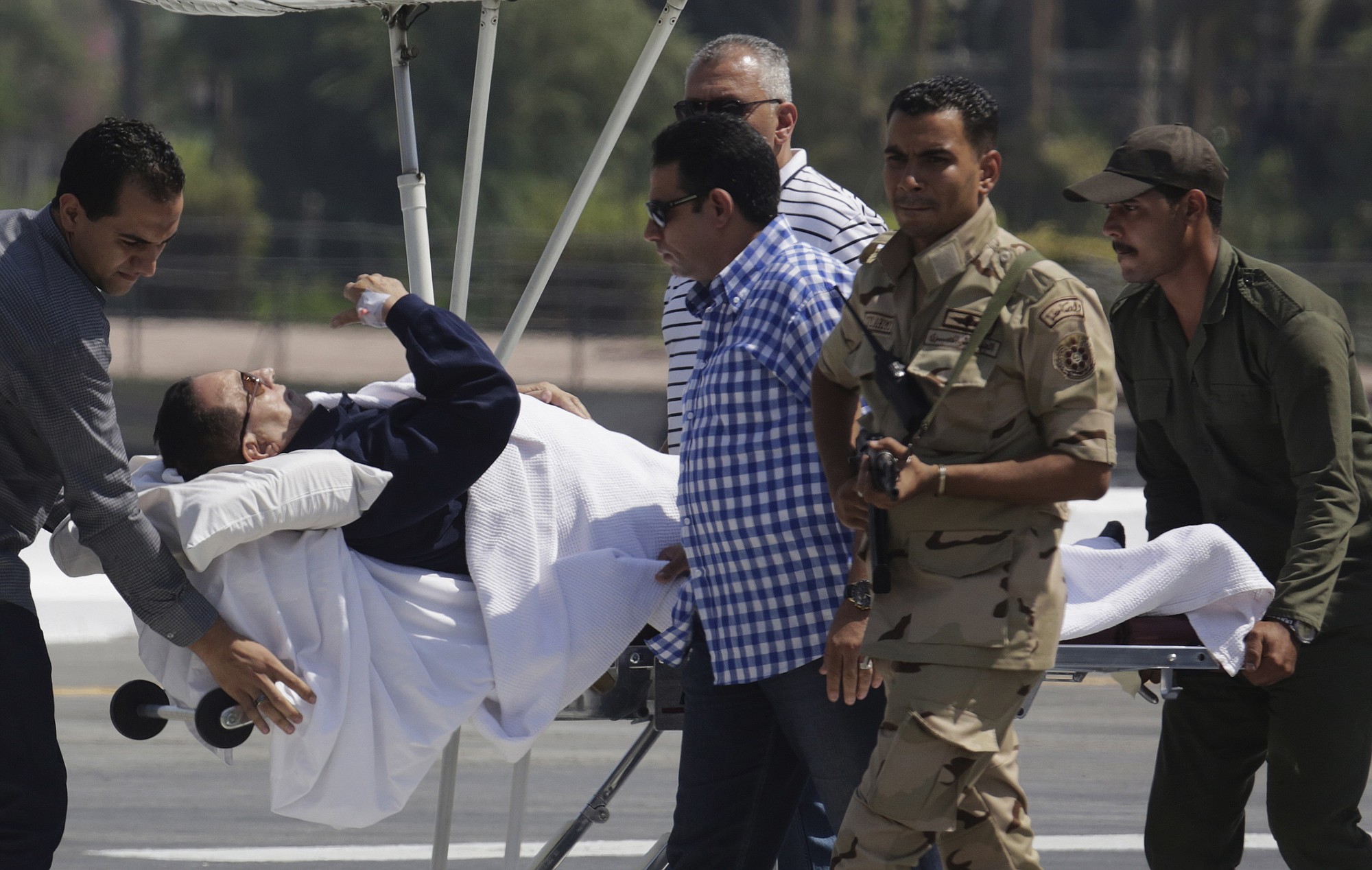Egyptian medics and army personnel escort former Egyptian President Hosni Mubarak, 86, from a helicopter ambulance after landing at the Maadi Military Hospital, following his retrial in Cairo, Egypt, Wednesday, Aug. 13, 2014. Egypt's deposed President Mubarak on Wednesday denied that he ordered protesters killed during an uprising in 2011, in his first lengthy speech to a court as his year-old retrial draws to an end.