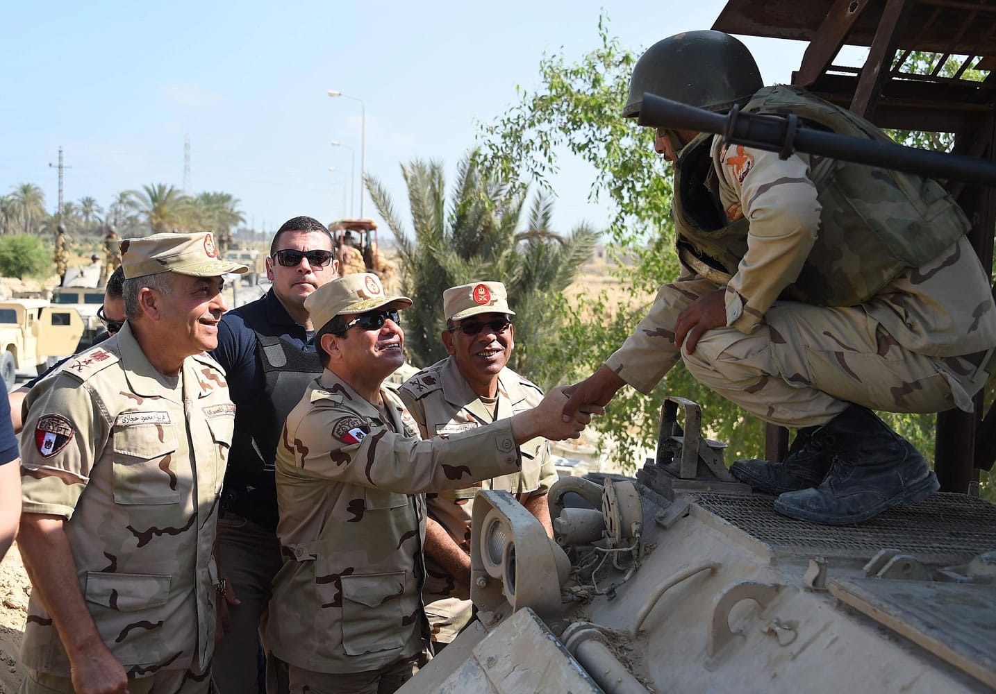In this picture provided by the office of the Egyptian Presidency, Egyptian President Abdel-Fattah el-Sissi, center, greets members of the Egyptian armed forces in Northern Sinai, Egypt, Saturday, July 4, 2015.