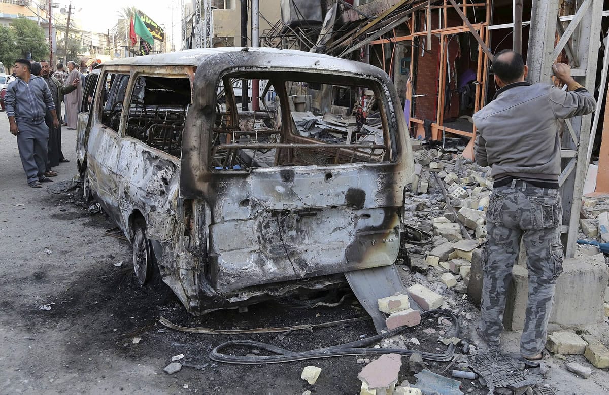 Civilians inspect the site of Friday's car bomb in Baghdad's Gorayaat neighborhood in Iraq on Saturday.