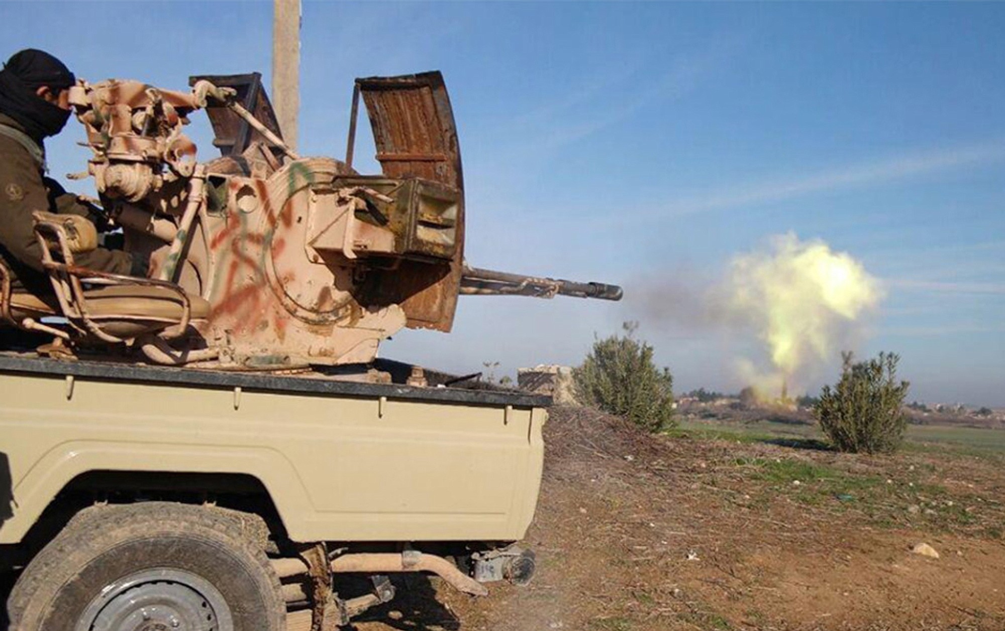 A fighter fires a heavy weapon mounted on the back of a pickup truck during fighting in Tal Tamr, Hassakeh province, Syria.