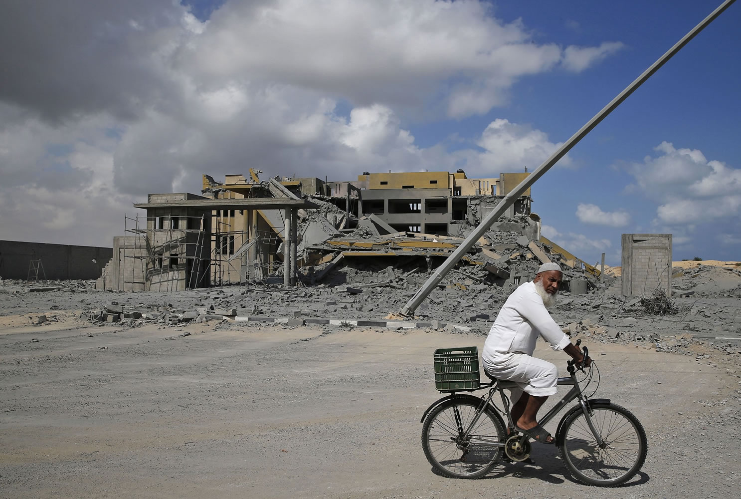 A Palestinian man cycles Tuesday past a transition center for newly released convicts, which was not yet operational and empty, destroyed by an overnight Israeli missile strike in Rafah, southern Gaza Strip.