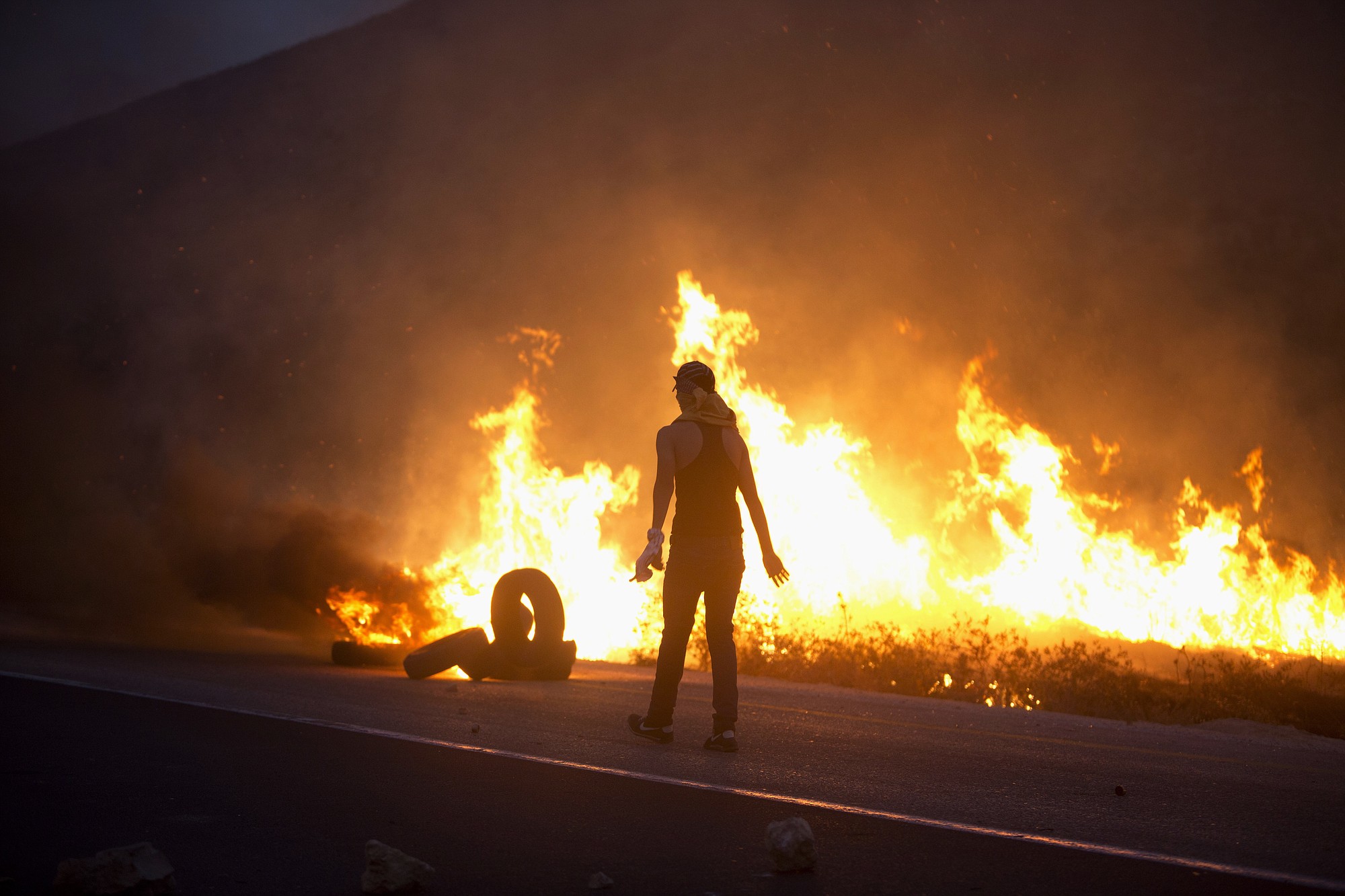 A Palestinian demonstrator burns tires in clashes with Israeli soldiers Sunday near the West Bank city of Nablus.