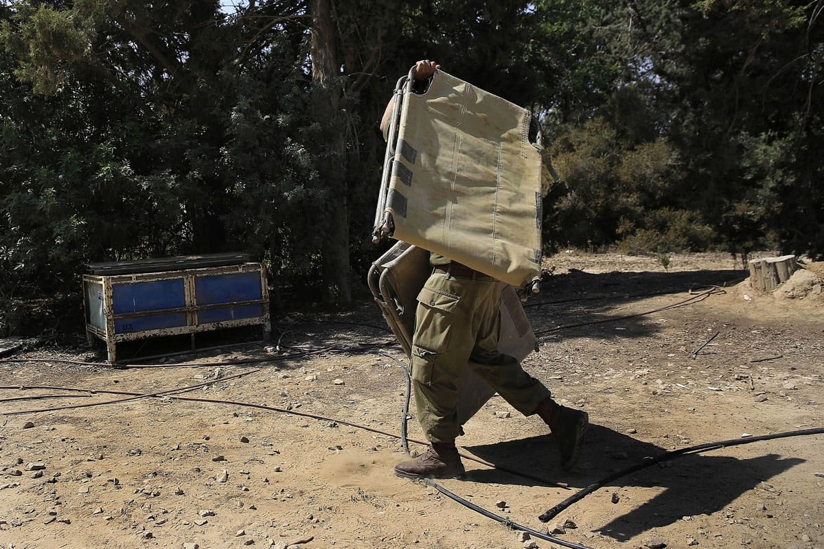 An Israeli soldier carries a bunk bed near the Israel Gaza border, Israel, on  Monday.