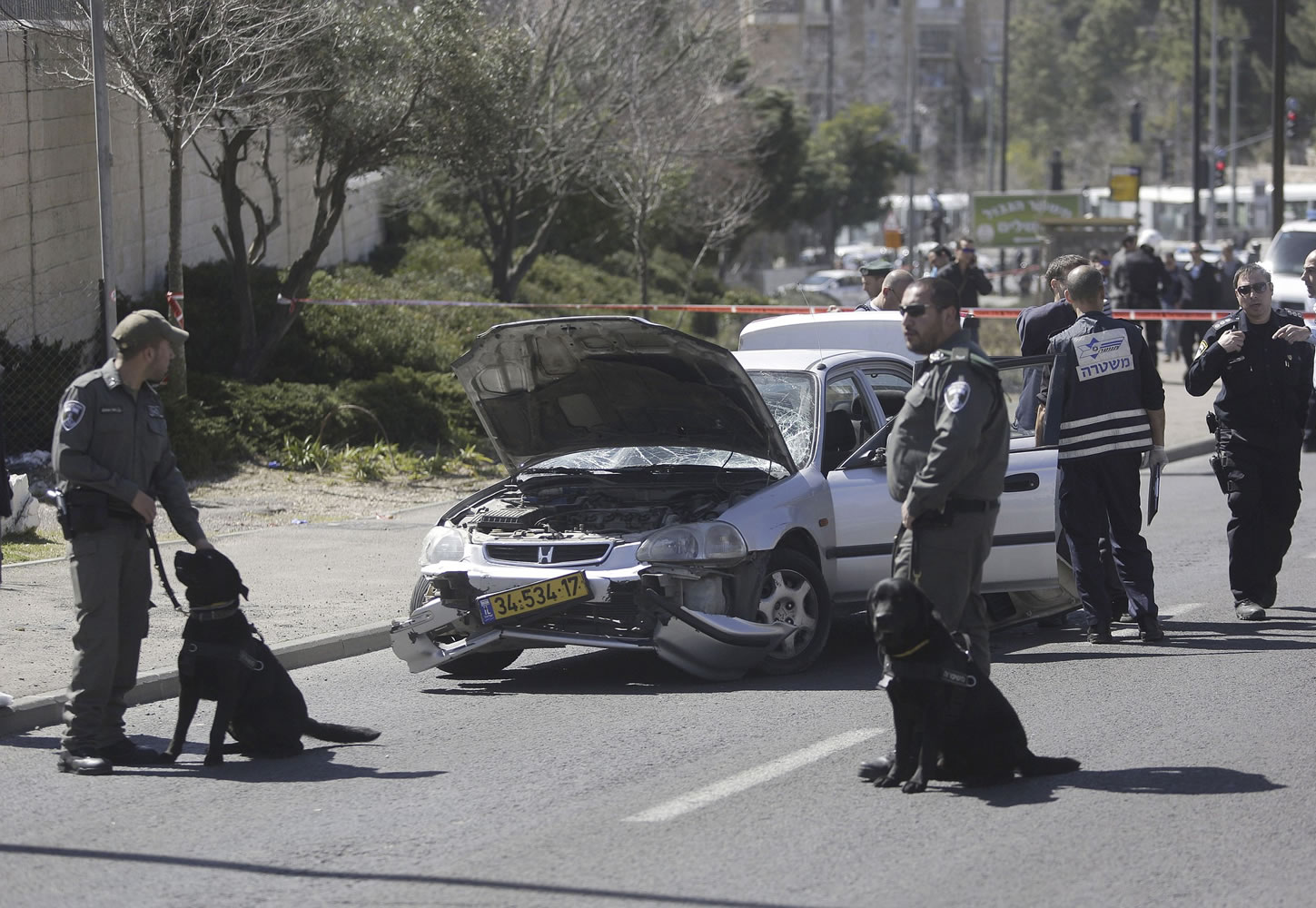 Israeli police stand next to a car Friday at the scene of an of an apparent attack in Jerusalem. Israeli police say a suspected Palestinian motorist has rammed his car into five people near a Jerusalem police station, injuring five, before he was shot and wounded by a security guard.
